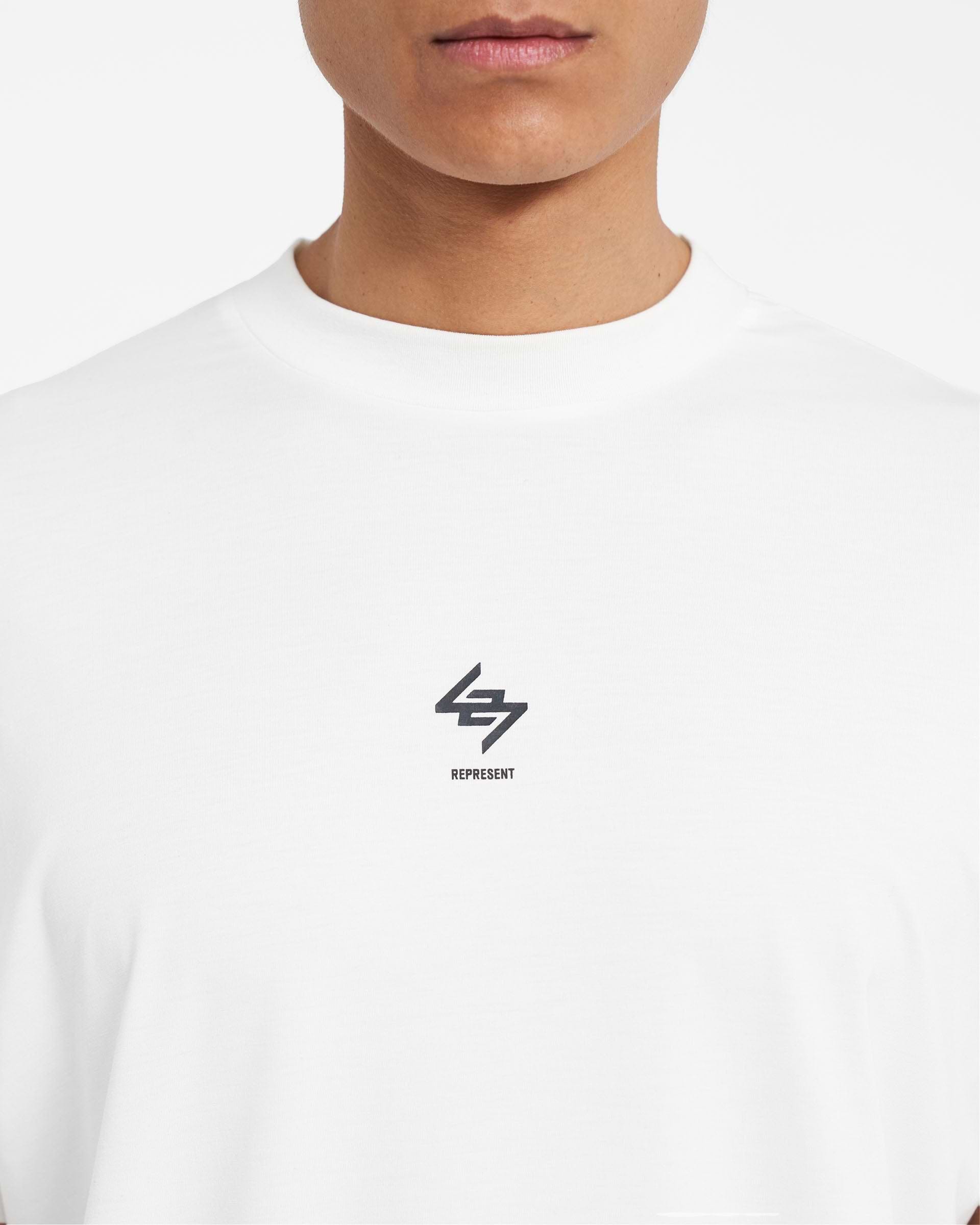 Man wearing a white tank top on a plain white background | 247 Oversized Tank in Flat White | Oversized tank with 4-way stretch | 247 T-Shirts | Represent Clo