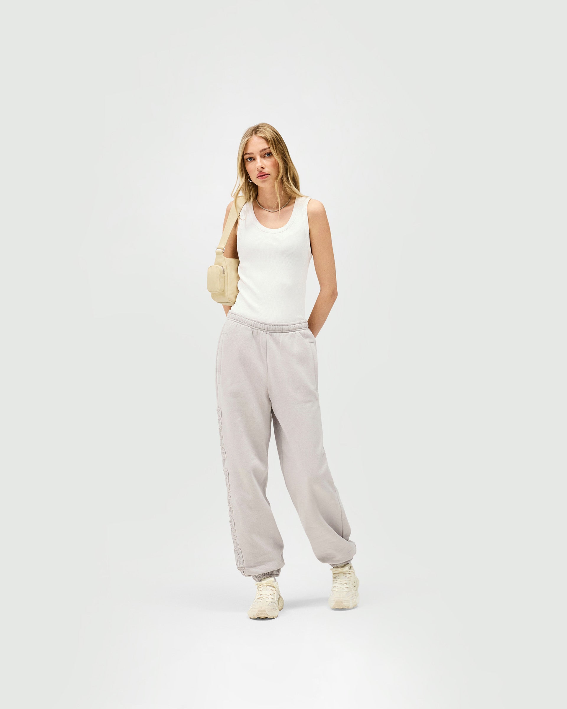 Woman wearing light grey jogger on a plain white background | Epic Jogger in Light Grey | Relaxed fit jogger with raw edge branding | Womens SS25 Bottoms | Represent Clo