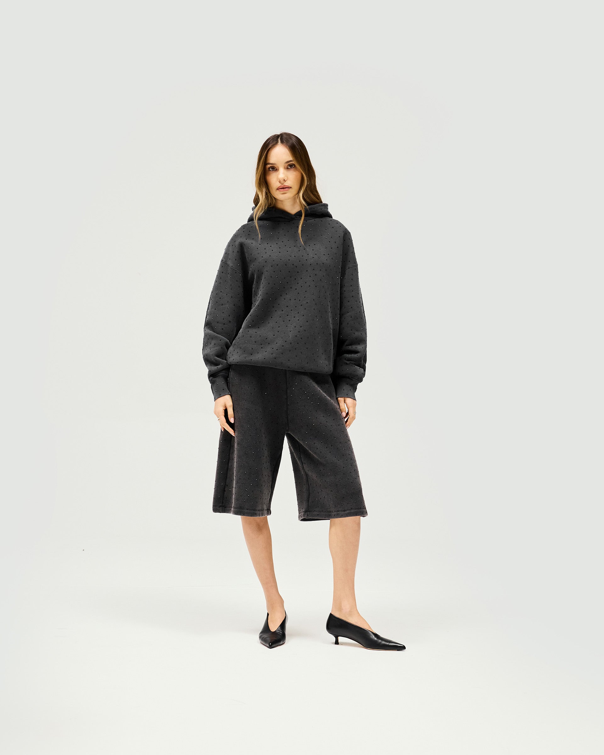 Woman wearing an oversized grey hoodie on a plain white background | Spark Hoodie in Washed Grey | Slouchy hoodie with all-over hotfix and silicon wash | SS25 Hoodies | Represent Clo