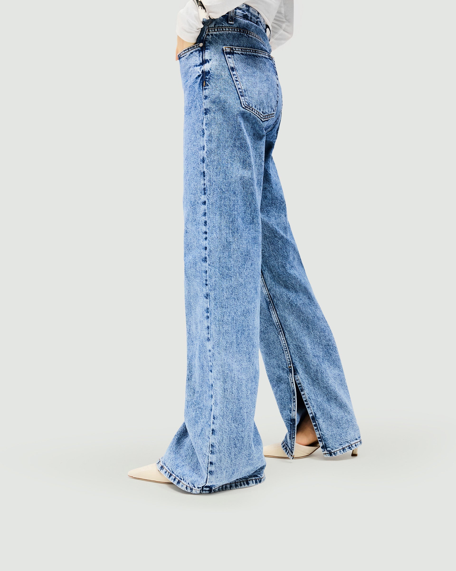 Woman wearing blue jeans on a plain white background | Split Hem Straight Jean in Washed Blue | Straight leg jeans with outside seam split | SS25 Womens Jeans | Represent Clo