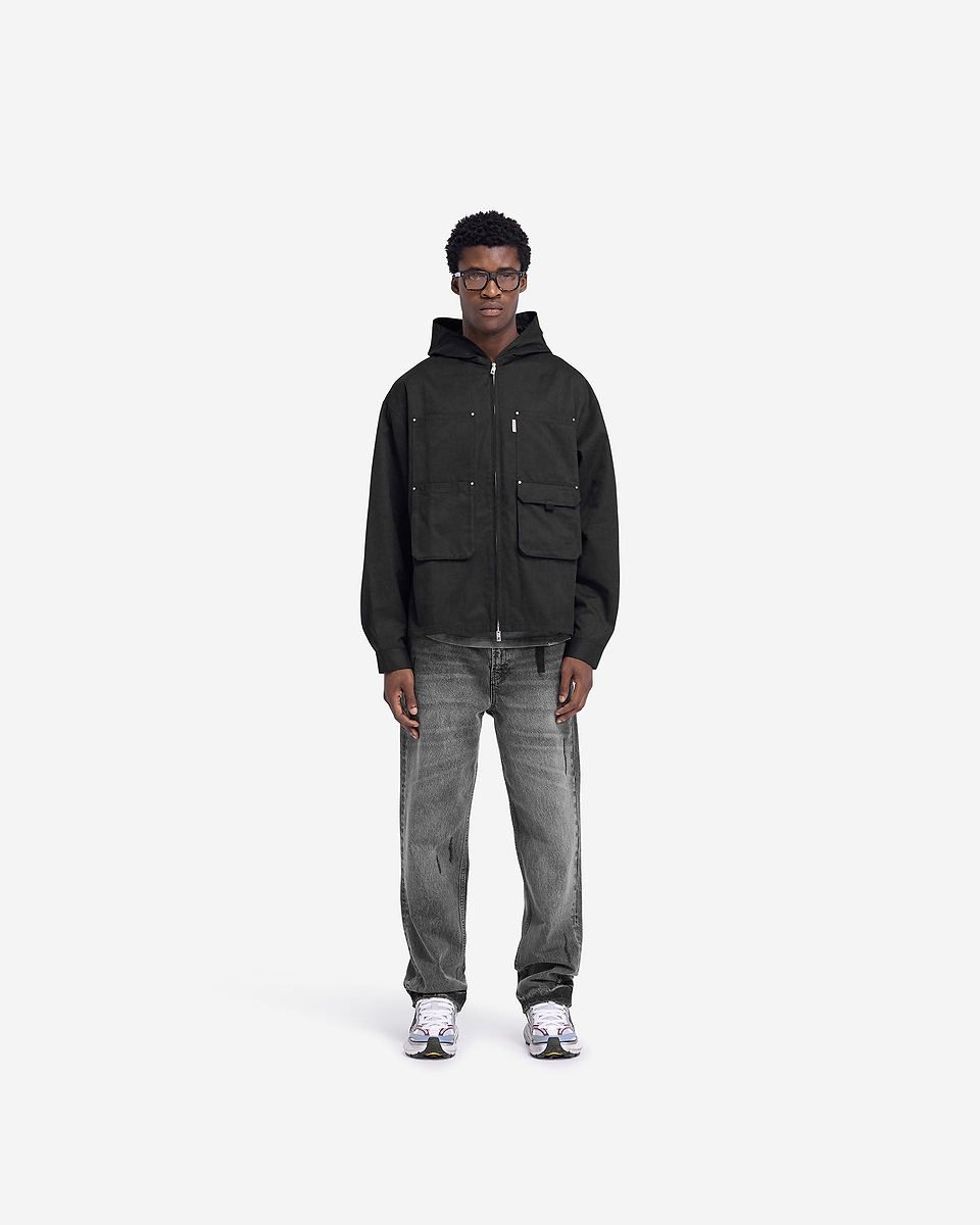 Man wearing a black utility hooded shirt on a plain white background | Utility Hooded Shirt in Jet Black | Hooded shirt with zip closure and multiple pockets | FW24 Shirts | Represent Clo