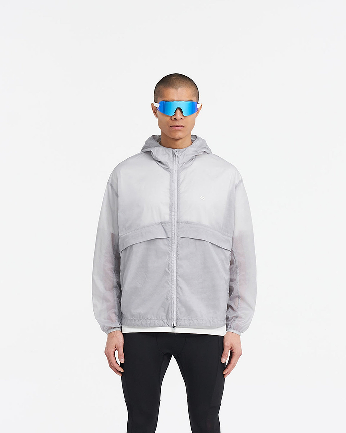 Man wearing a moonstone hooded training jacket on a plain white background | 247 Hooded Training Jacket in Moonstone | Translucent nylon ripstop outerwear with DWR coating | 247 Outerwear | Represent Clo