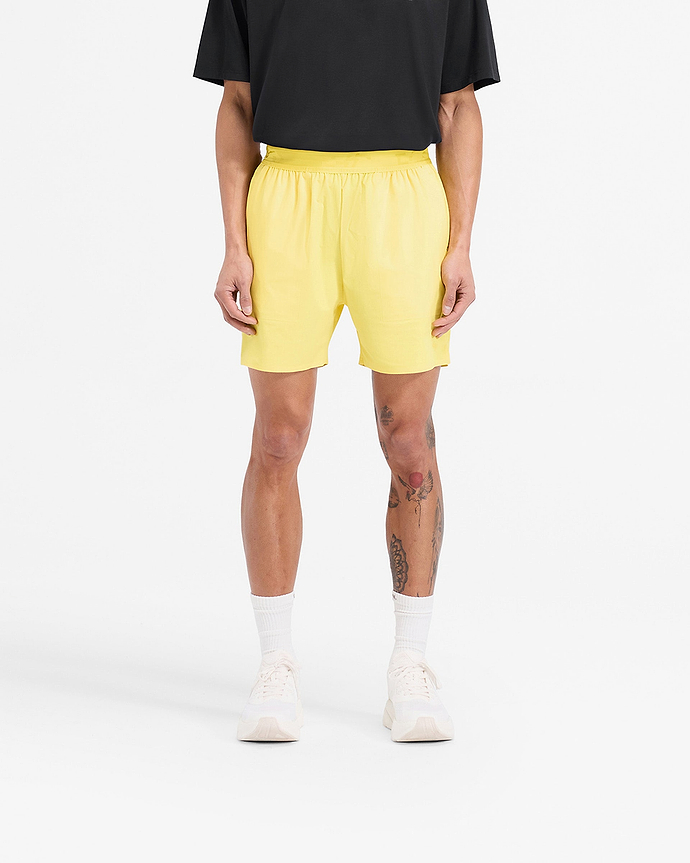 Man wearing yellow training shorts on a plain white background | Team 247 Fused Shorts in Lemon | Gym shorts with internal drawcords and quick drying fabric | 247 Shorts | Represent Clo