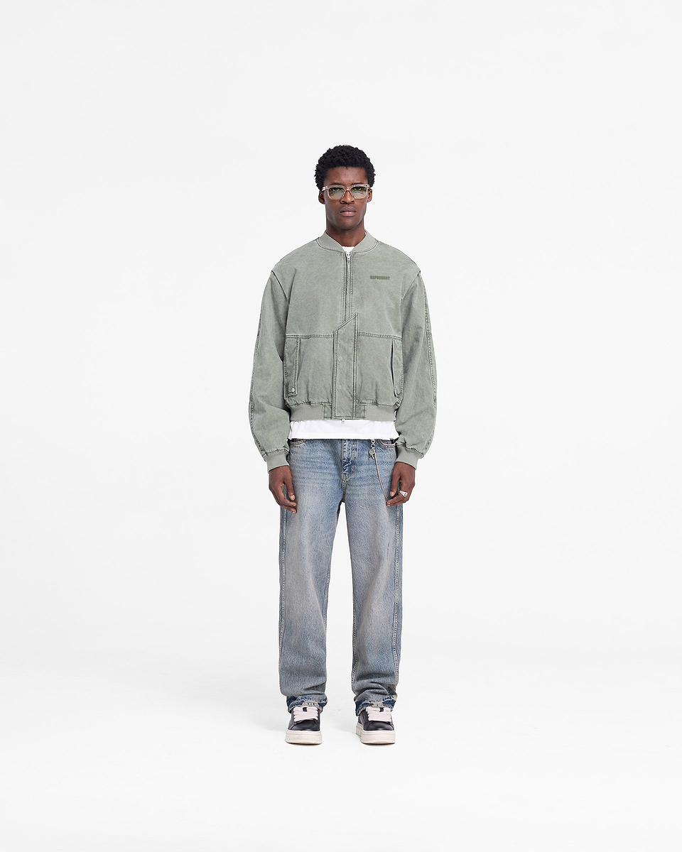 Man wearing a khaki bomber jacket on a plain white background | Inset Sleeve Bomber in Khaki | Cotton bomber with asymmetric placket and shoulder gussets | FW24 Outerwear | Represent Clo