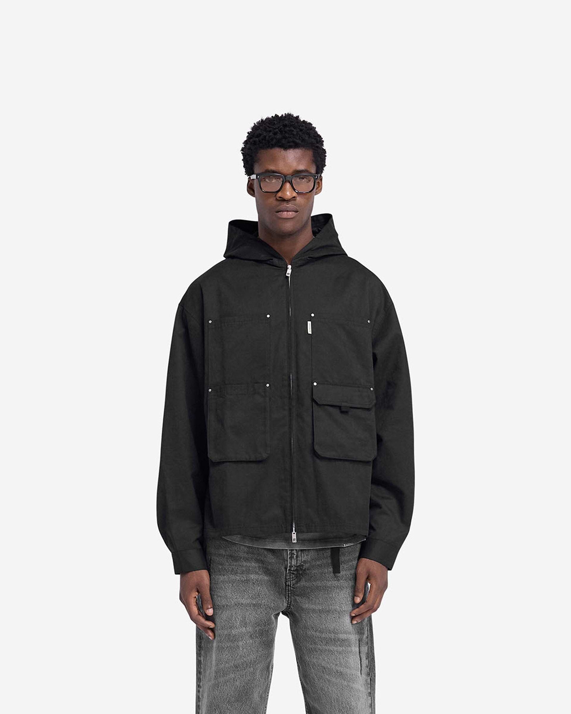 Man wearing a black hooded utility shirt on a plain white background | Utility Hooded Shirt in Jet Black | Hooded shirt with multiple pockets and double zip | FW24 Shirts | Represent Clo
