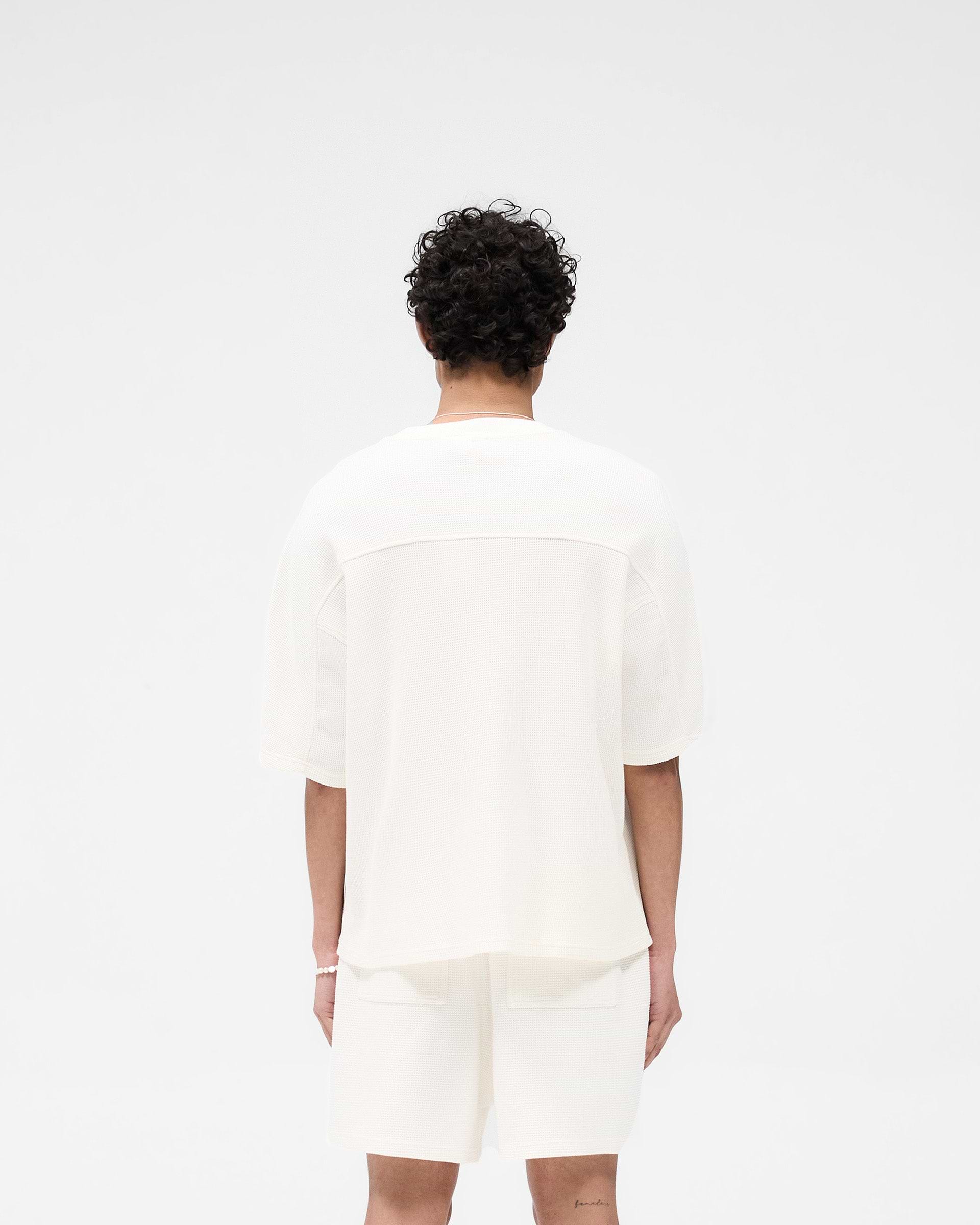 Man wearing a white waffle t-shirt on a plain white background | Waffle T-Shirt in Flat White | Boxy fit cotton t-shirt with interlock waffle fabric | SS25 T-Shirts | Represent Clo