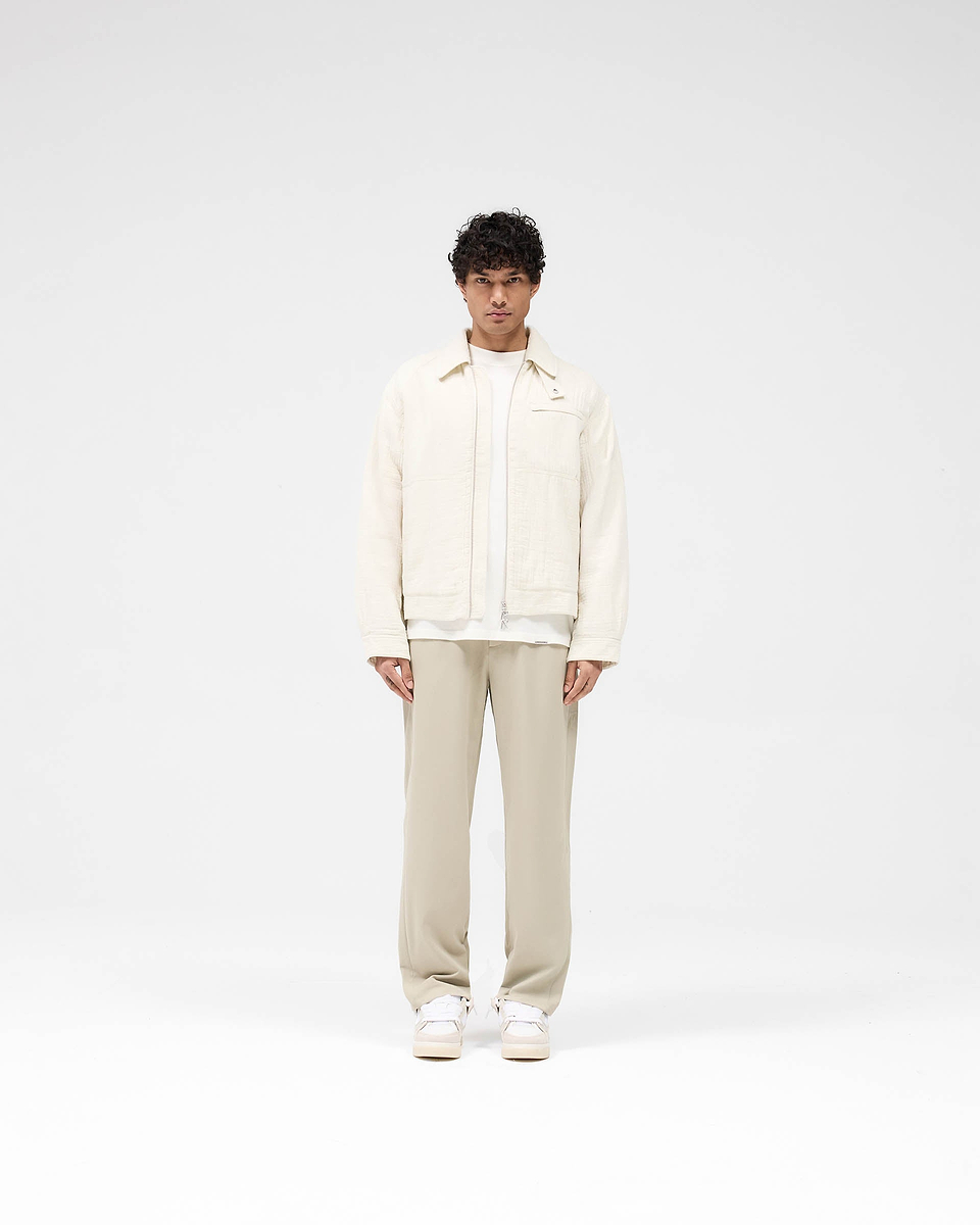 Man wearing an ecru jacket on a plain white background | Crinkle Trucker Jacket in Ecru | Oversized cotton outerwear with charm zip | SS25 Outerwear | Represent Clo