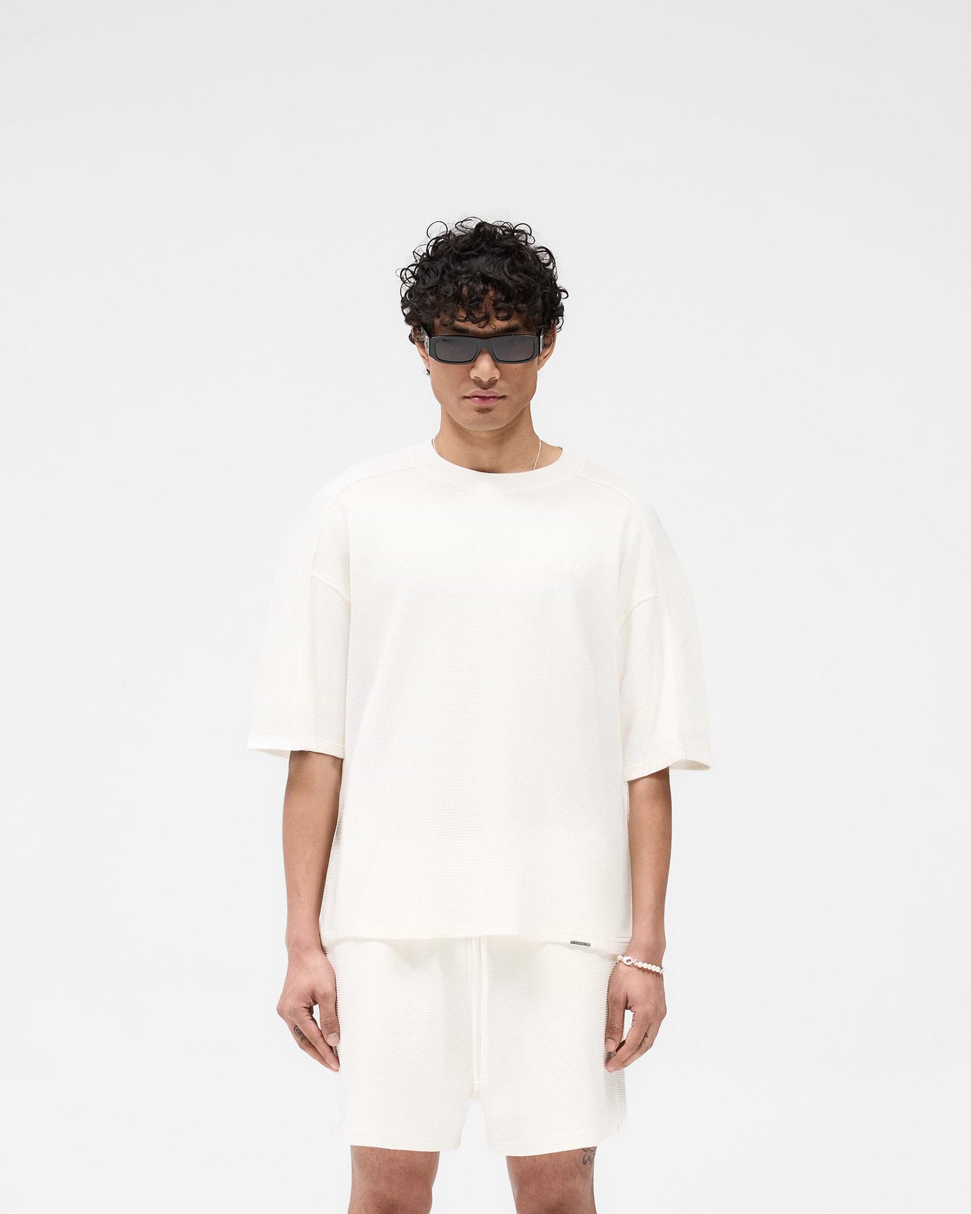 Man wearing a white t-shirt on a plain white background | Waffle T-Shirt in Flat White | Boxy fit t-shirt with interlock waffle fabric | SS25 T-Shirts | Represent Clo