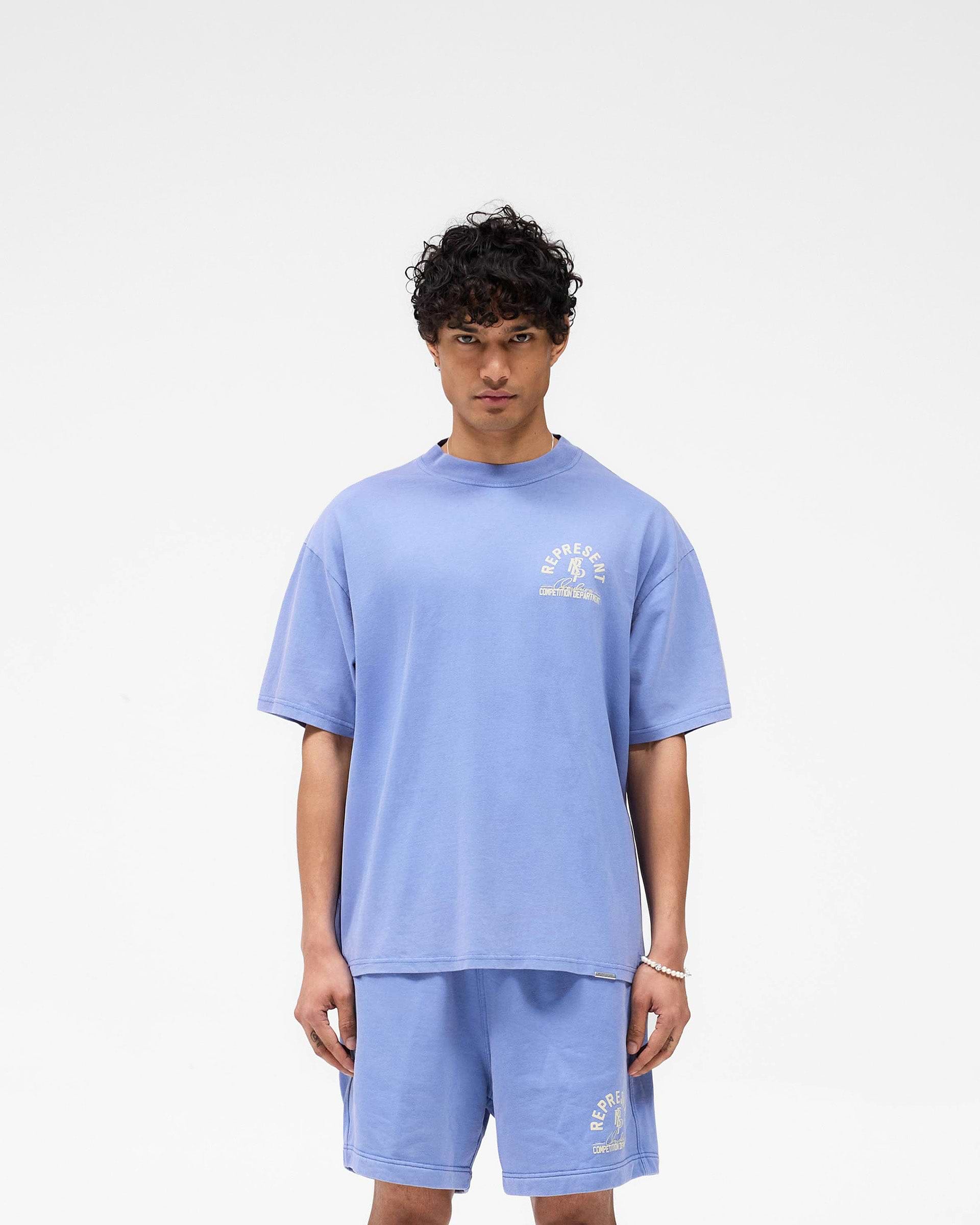 Man wearing a bright blue t-shirt on a plain white background | Competition Department T-Shirt in Bright Blue | Oversized t-shirt with ribbed neckline and chest graphic | SS25 T-Shirts | Represent Clo