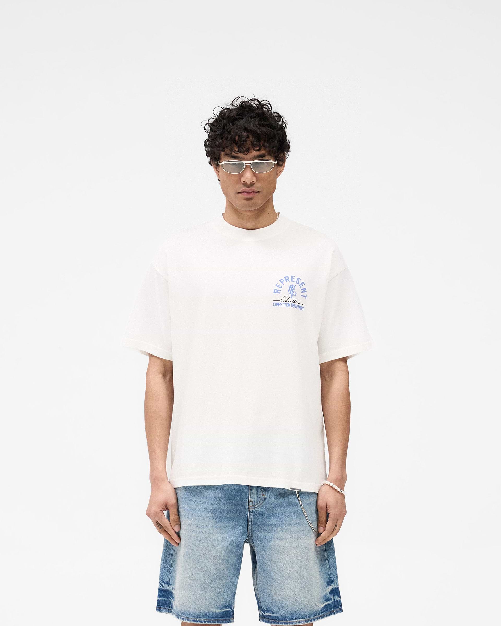 Man wearing an oversized white t-shirt on a plain white background | Competition Department T-Shirt in Flat White | Oversized t-shirt with chest graphic and raw-edge hem | SS25 T-Shirts | Represent Clo