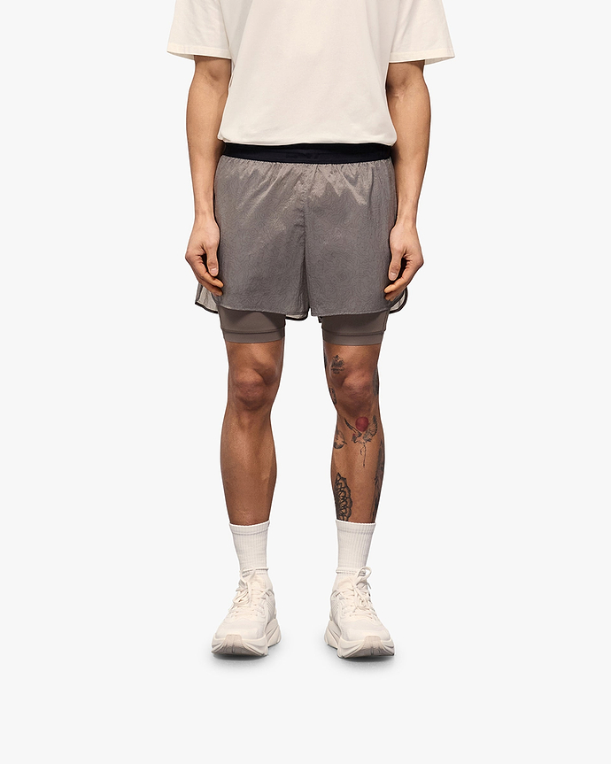 Man wearing a grey 2-in-1 run shorts on a plain white background | 247 Contour 2-In-1 Run Shorts in Pebble | Run shorts with inner legging and zip pockets | 247 Shorts | Represent Clo