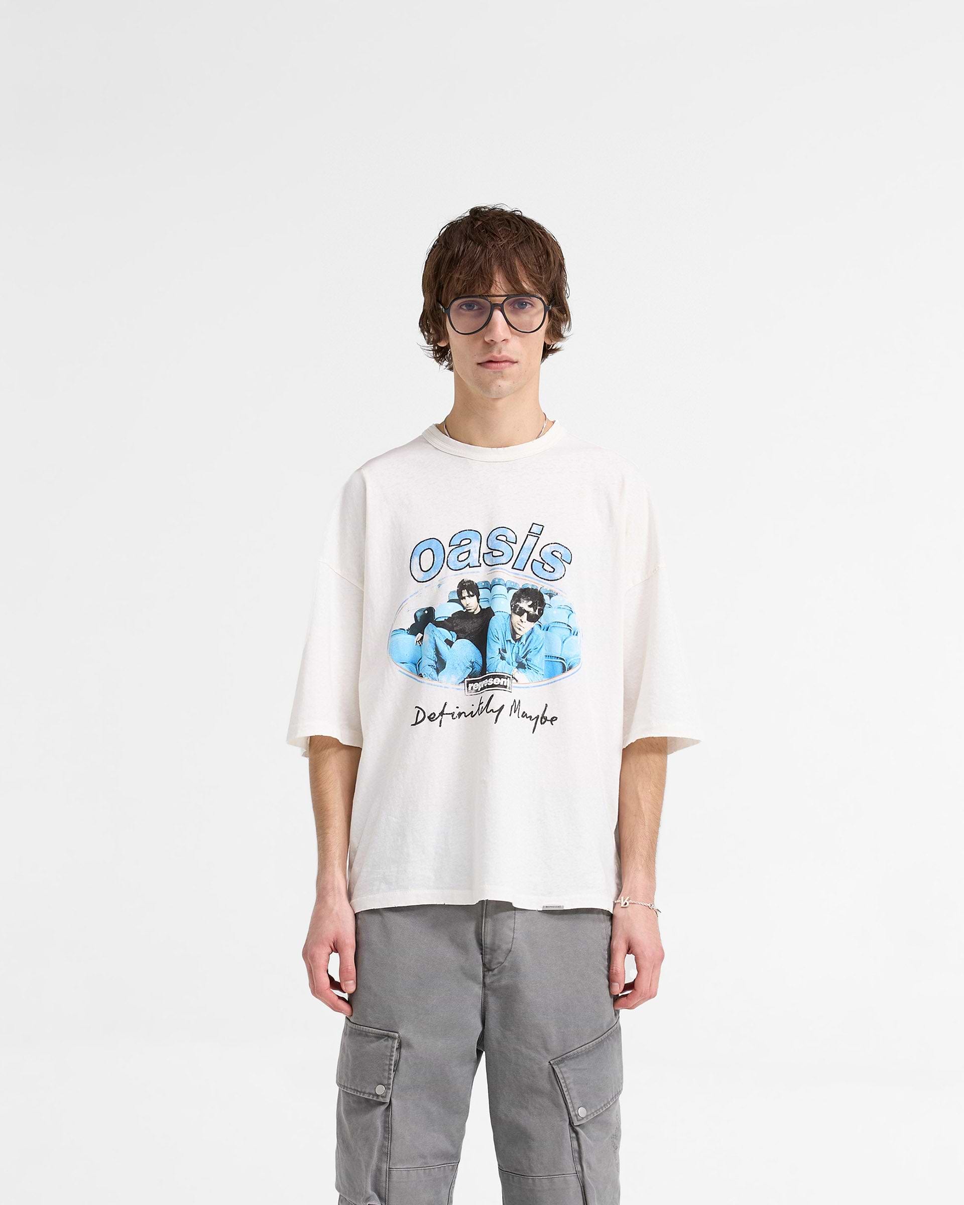 Man wearing a white t-shirt with graphics on a plain white background | Represent X Oasis Maine Road T-Shirt in Flat White | Oversized boxy t-shirt with distressed Oasis imagery | FW24 T-Shirts | Represent Clo