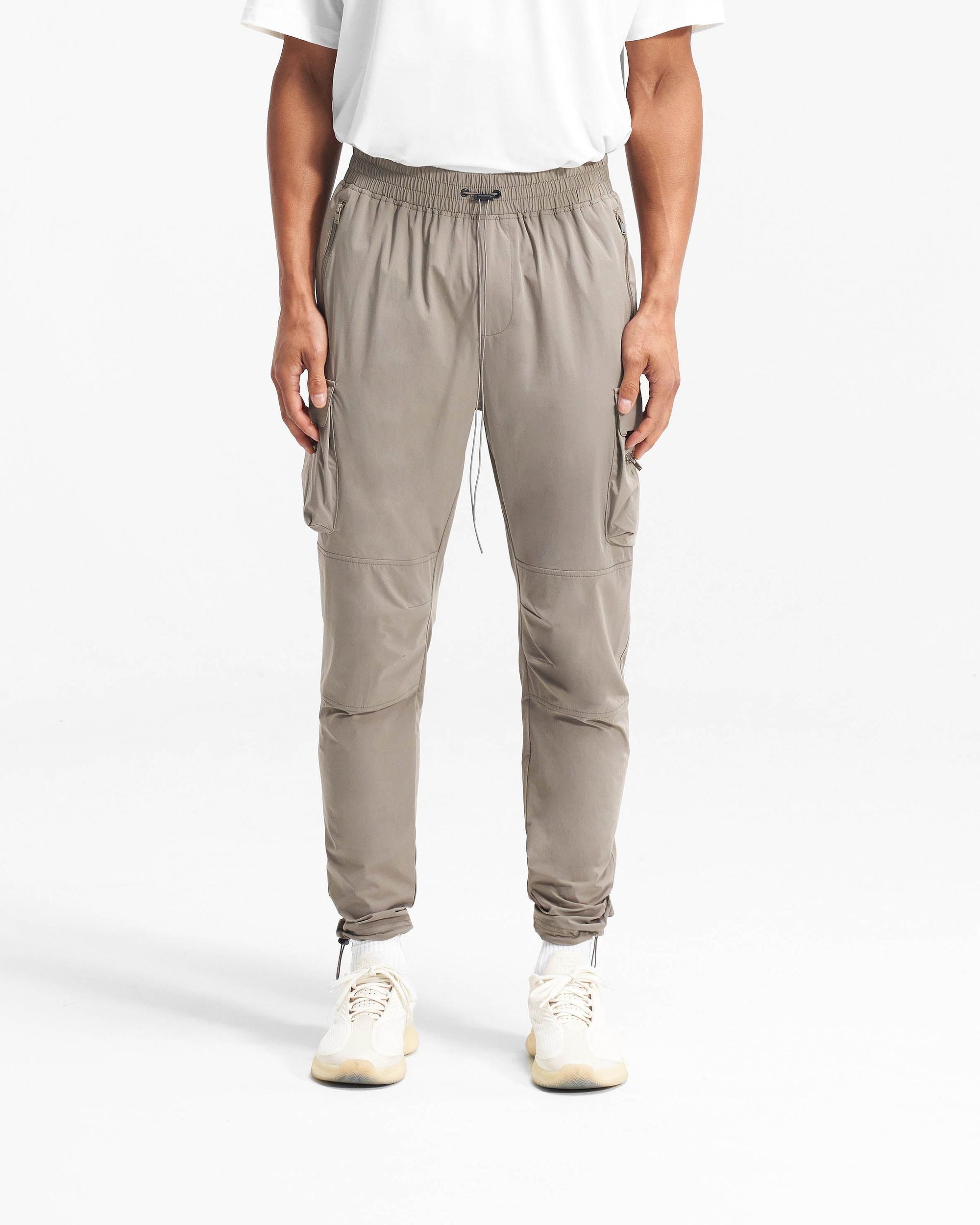 Man wearing taupe pants on a plain white background | 247 Pant in Taupe | Cargo pants with 4-way stretch nylon and cargo pockets | 247 Pants | Represent Clo