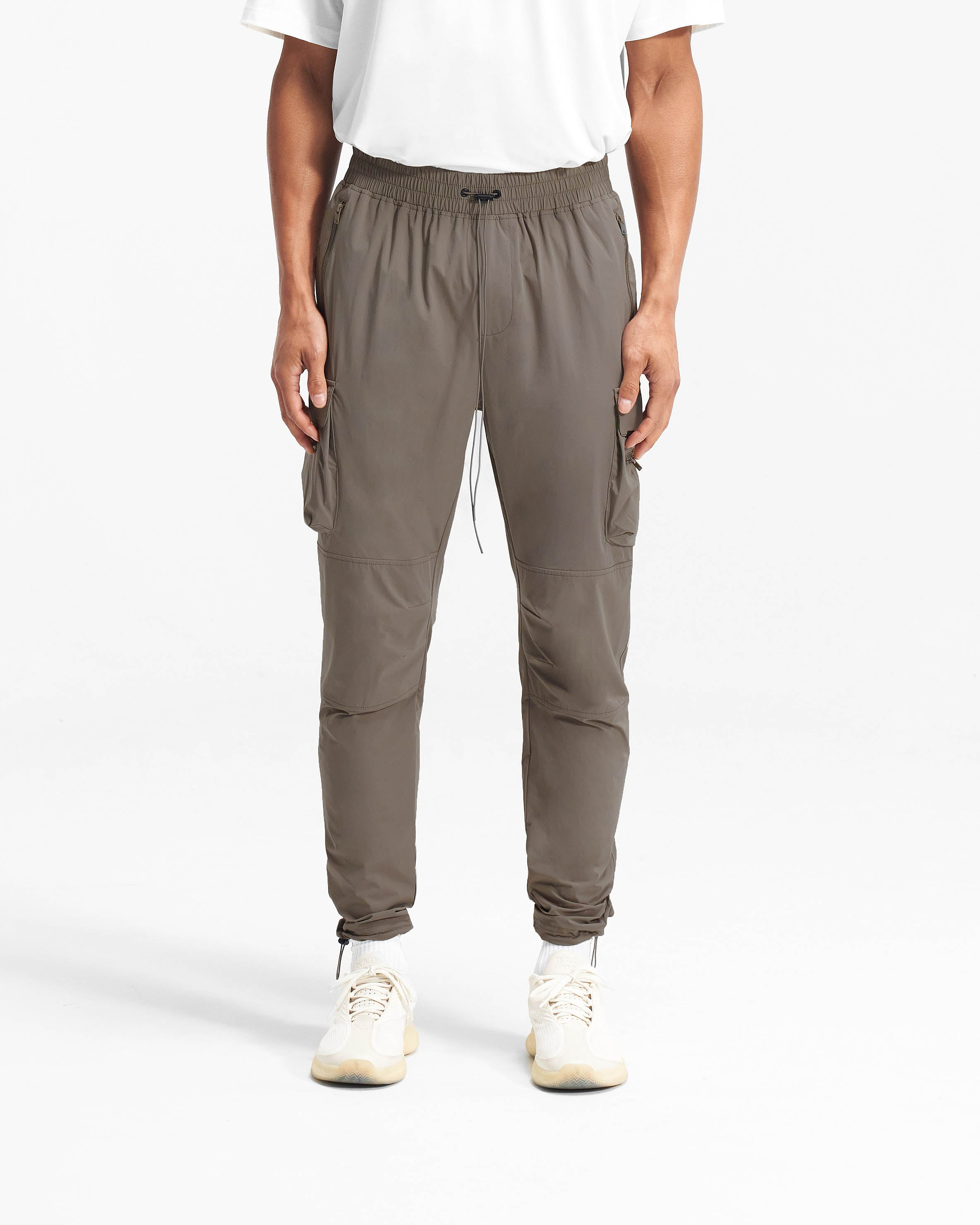 Man wearing olive cargo pants on a plain white background | 247 Pant in Olive | Versatile cargo pants with 4-way stretch and zip side pockets | 247 Pants | Represent Clo