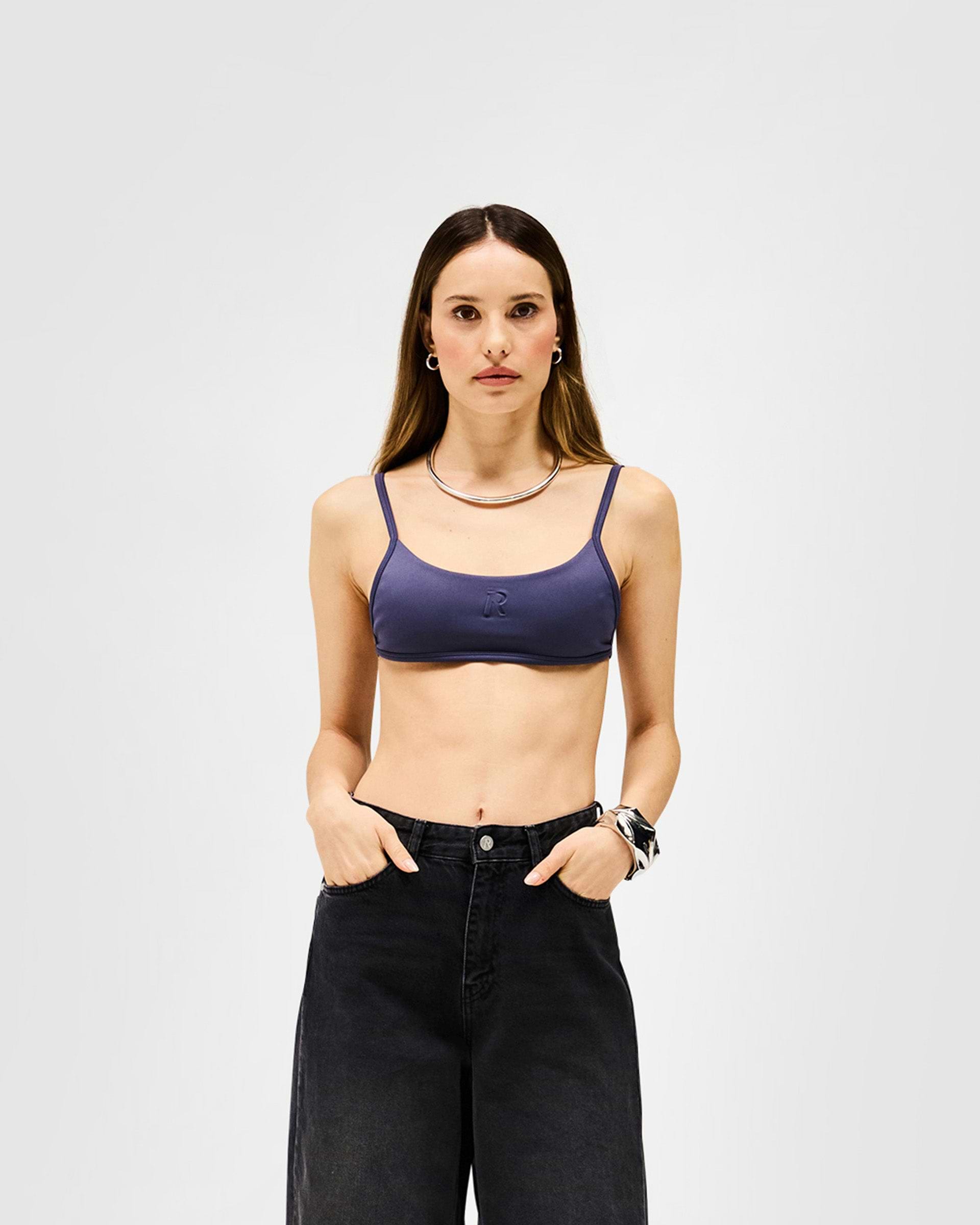Woman wearing a grey bralette on a plain white background | Control Bralette in Graphite | Neoprene bralette with adjustable fit and embossed Initial R | Womens SS25 Tops | Represent Clo