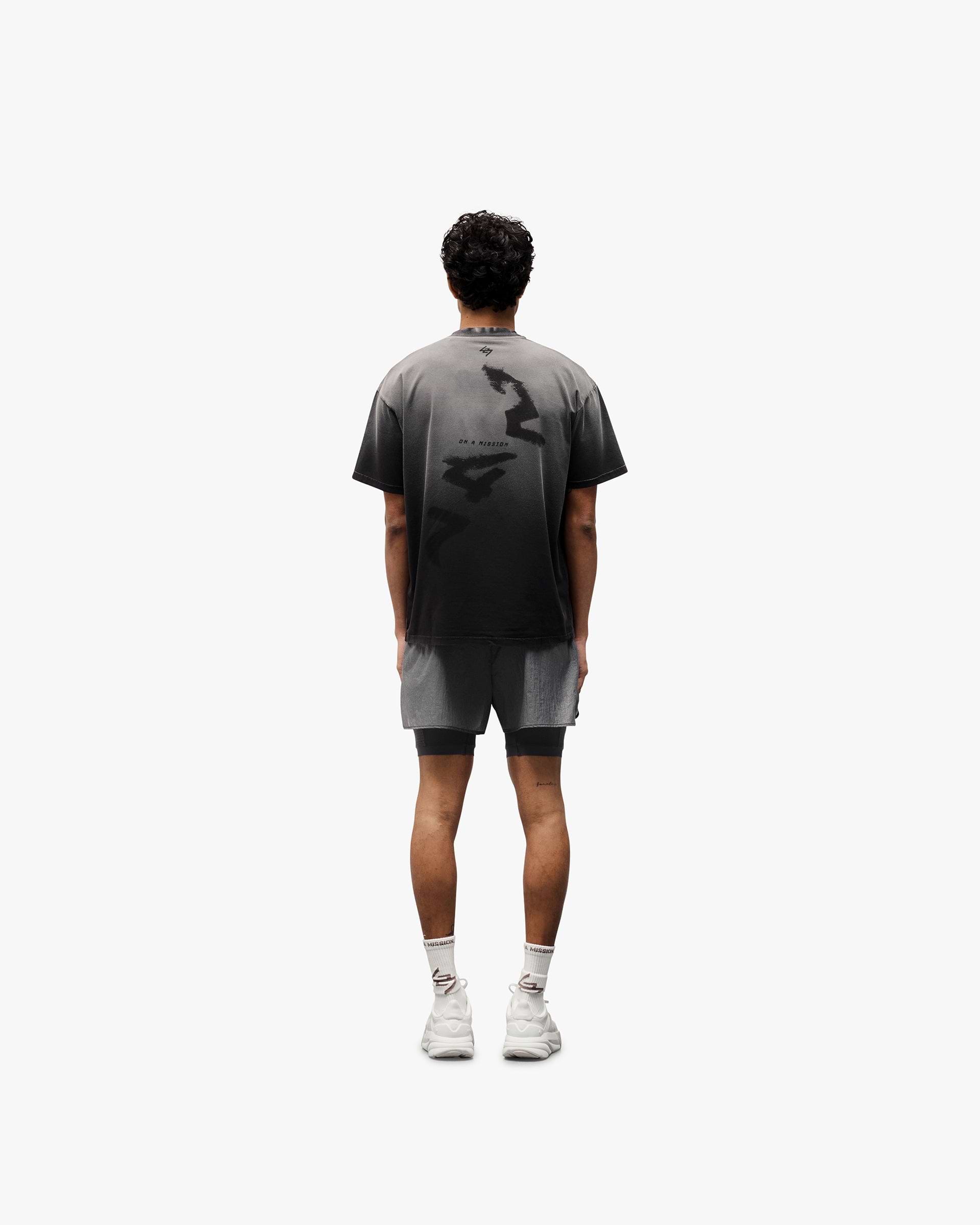 Man wearing an oversized black t-shirt on a plain white background | 247 Motion Oversized T-Shirt in Aged Black | Cotton blend t-shirt with graphic print | 247 T-Shirts | Represent Clo