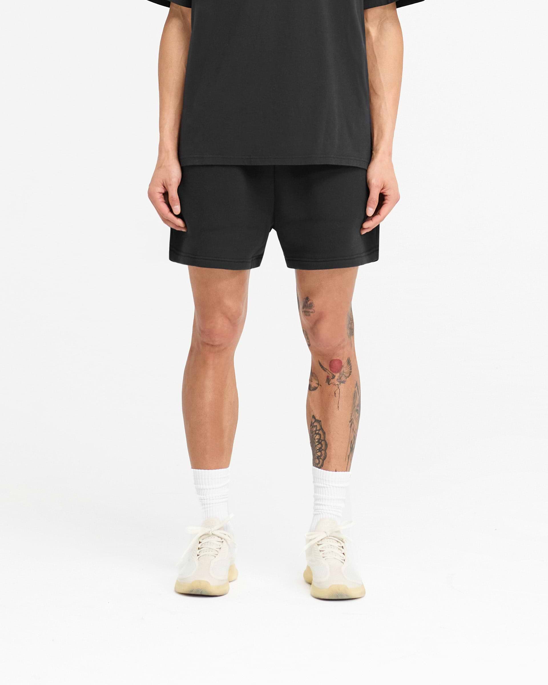 Man wearing off black jersey shorts on a plain white background | 247 X Everlast Training Camp Jersey Shorts in Off Black | Shorts with elasticated waistband and graphic design | 247 Shorts | Represent Clo
