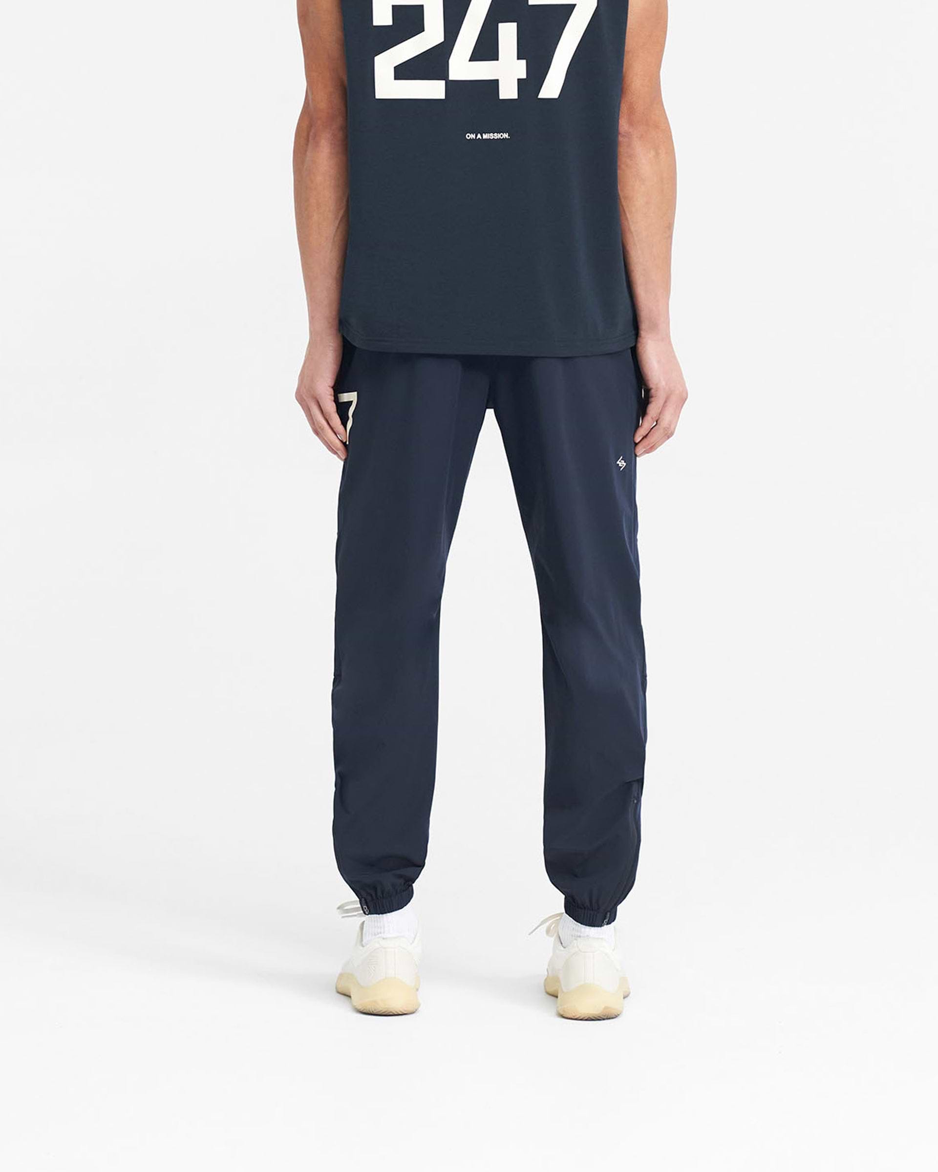 Man wearing navy training pants on a plain white background | 247 Training Pant in Navy | Nylon elastane pants with zip side and back pockets | 247 Pants | Represent Clo