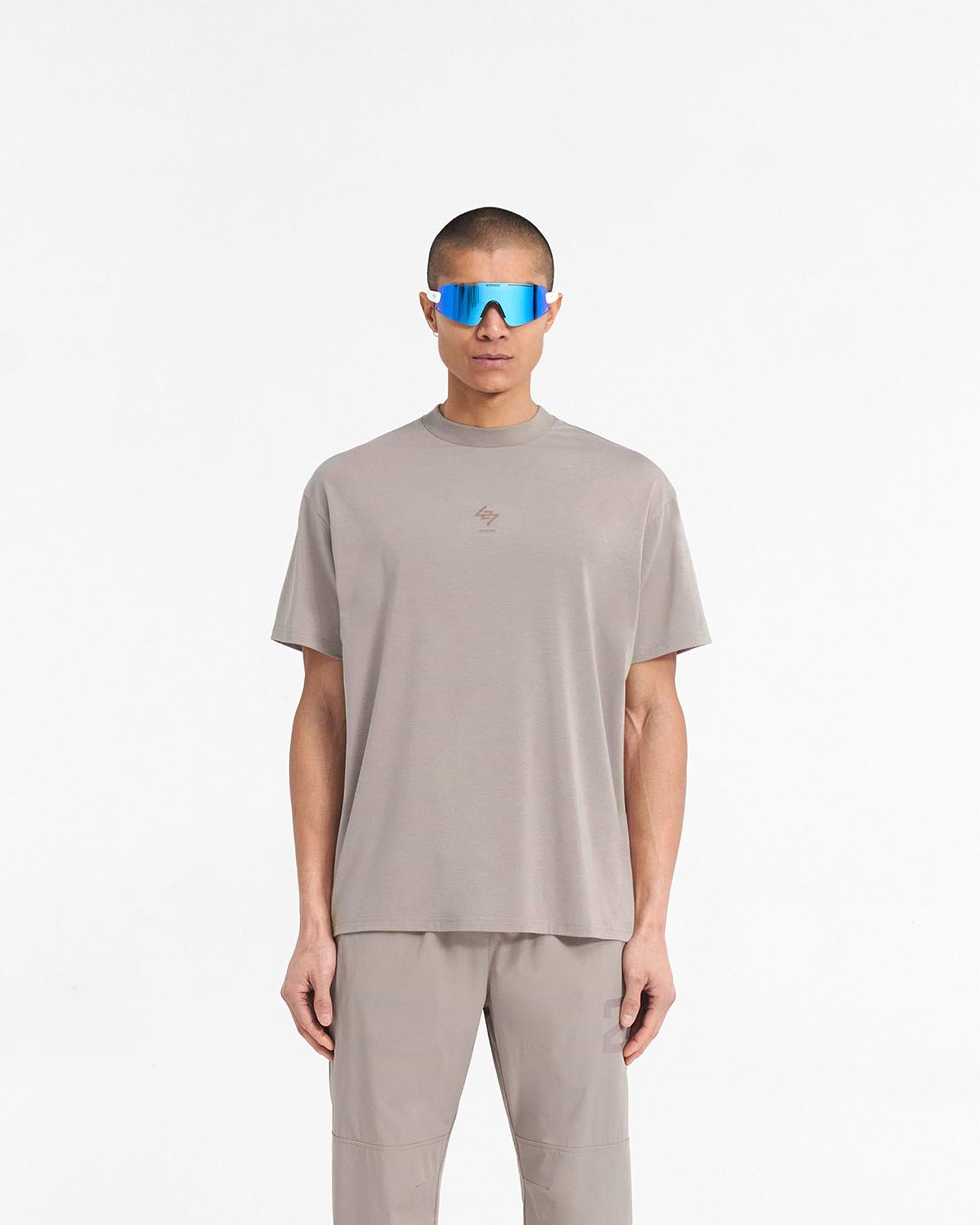 Man wearing an oversized grey t-shirt on a plain white background | 247 Oversized T-Shirt in Cinder | Gym t-shirt with 4-way stretch and quick dry fabric | 247 T-Shirts | Represent Clo