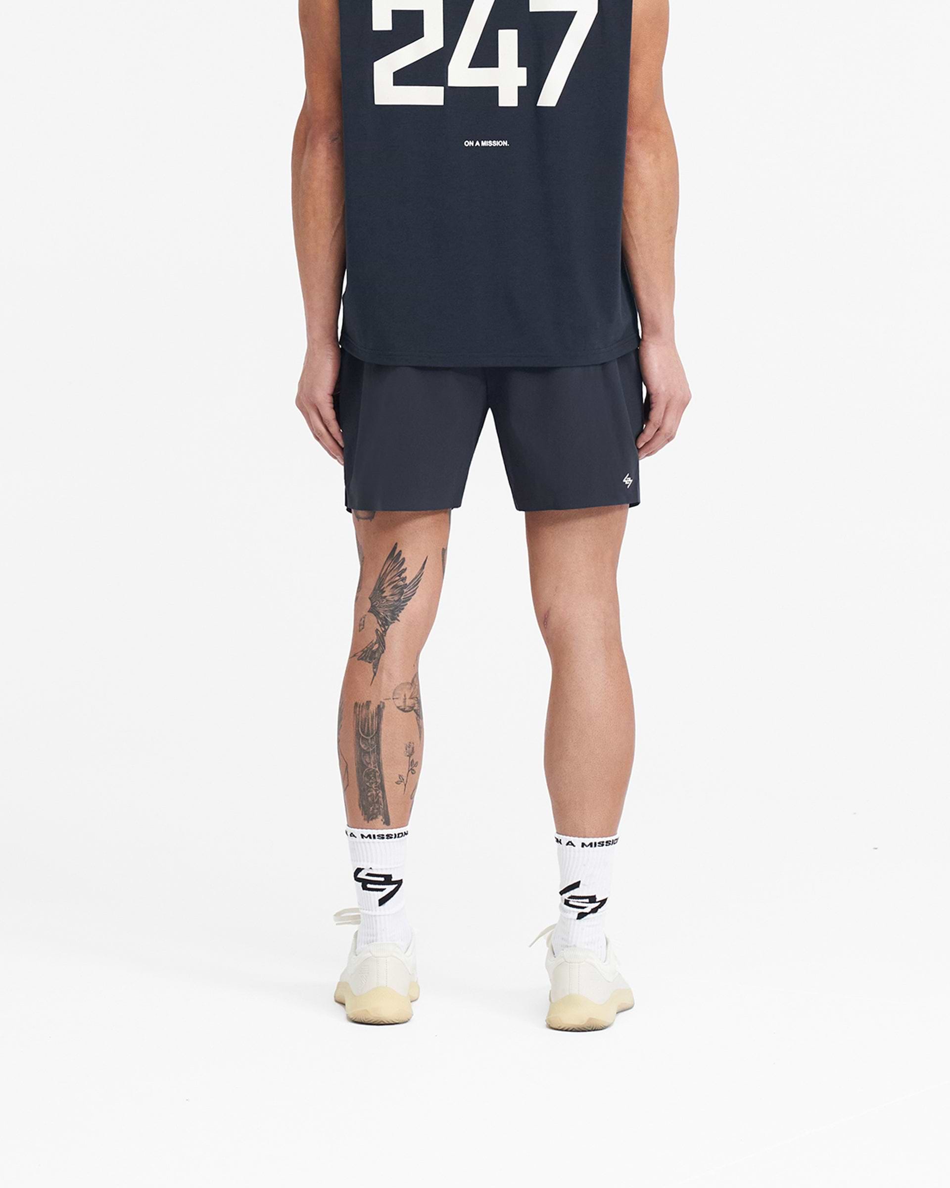 Man wearing navy gym shorts on a plain white background | 247 Fused Shorts in Navy | Gym shorts with 247 branding and adjustable waistband | 247 Shorts | Represent Clo