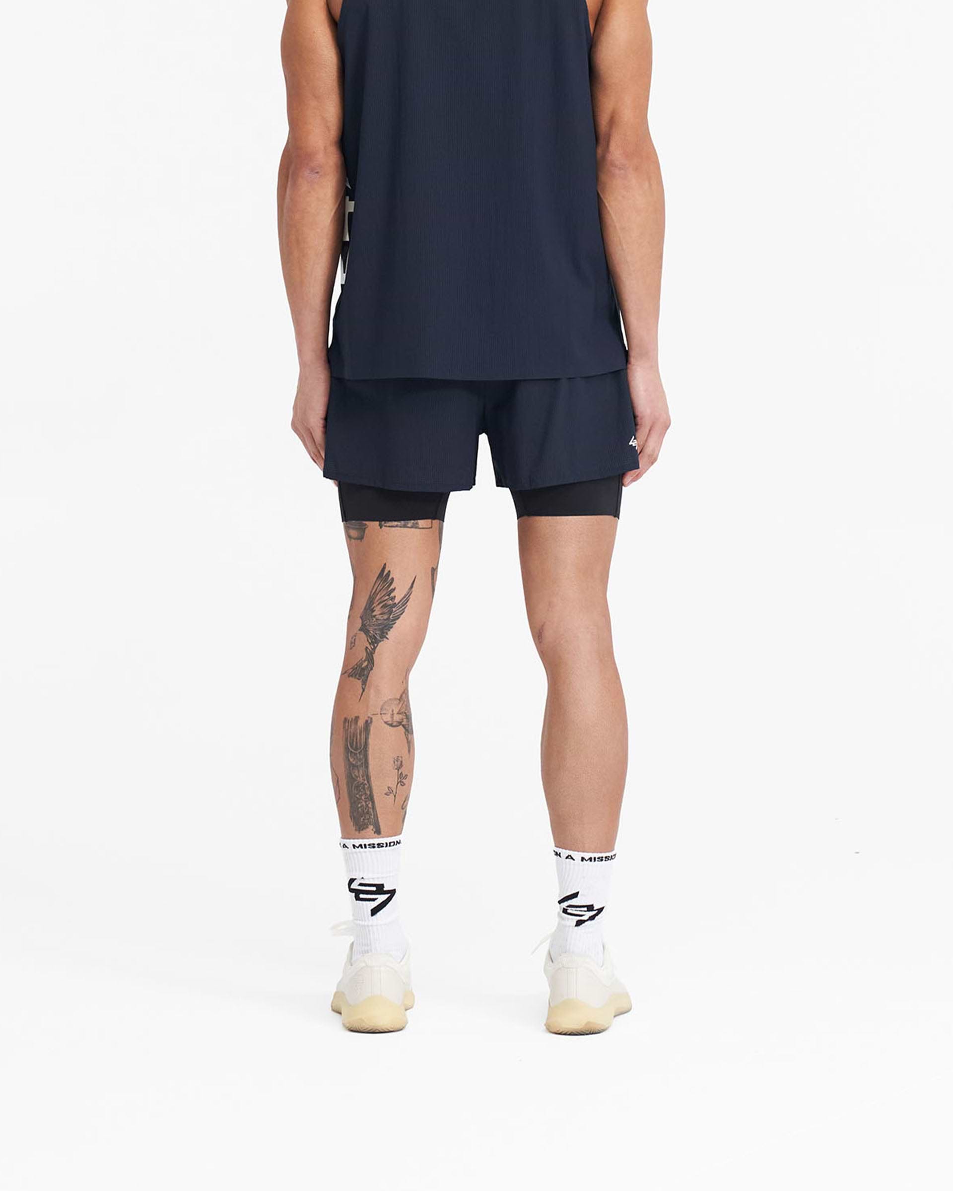 Man wearing navy trail shorts on a plain white background | 247 Trail Short in Navy | 2-in-1 shorts with stretch ripstop outer and internal tight | 247 Shorts | Represent Clo
