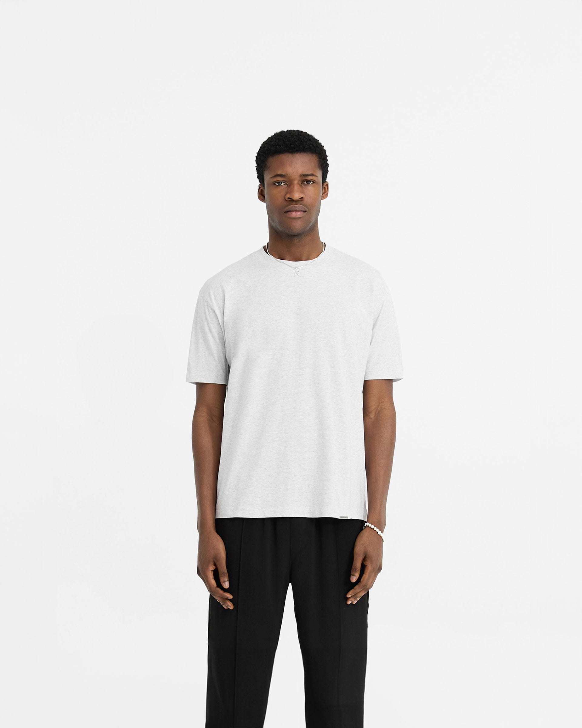 Man wearing a grey t-shirt on a plain white background | Initial T-Shirt in Ice Grey Marl | Regular fit t-shirt with shorter sleeves | Initial T-Shirts | Represent Clo