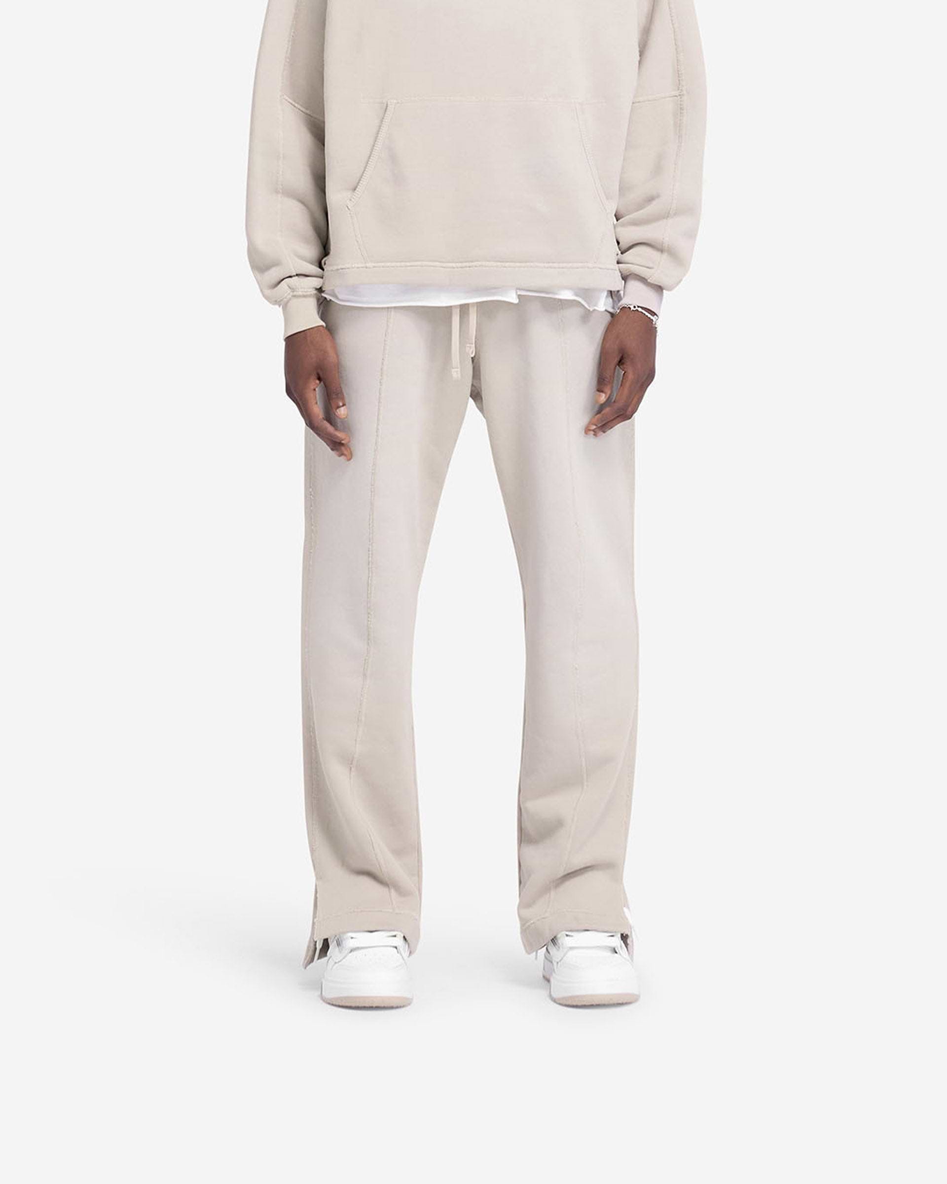 Man wearing oat sweatpants on a plain white background | Stepped Hem Sweatpants in Oat | Wide leg sweatpants with stepped hem and sun fade wash | FW24 Pants | Represent Clo