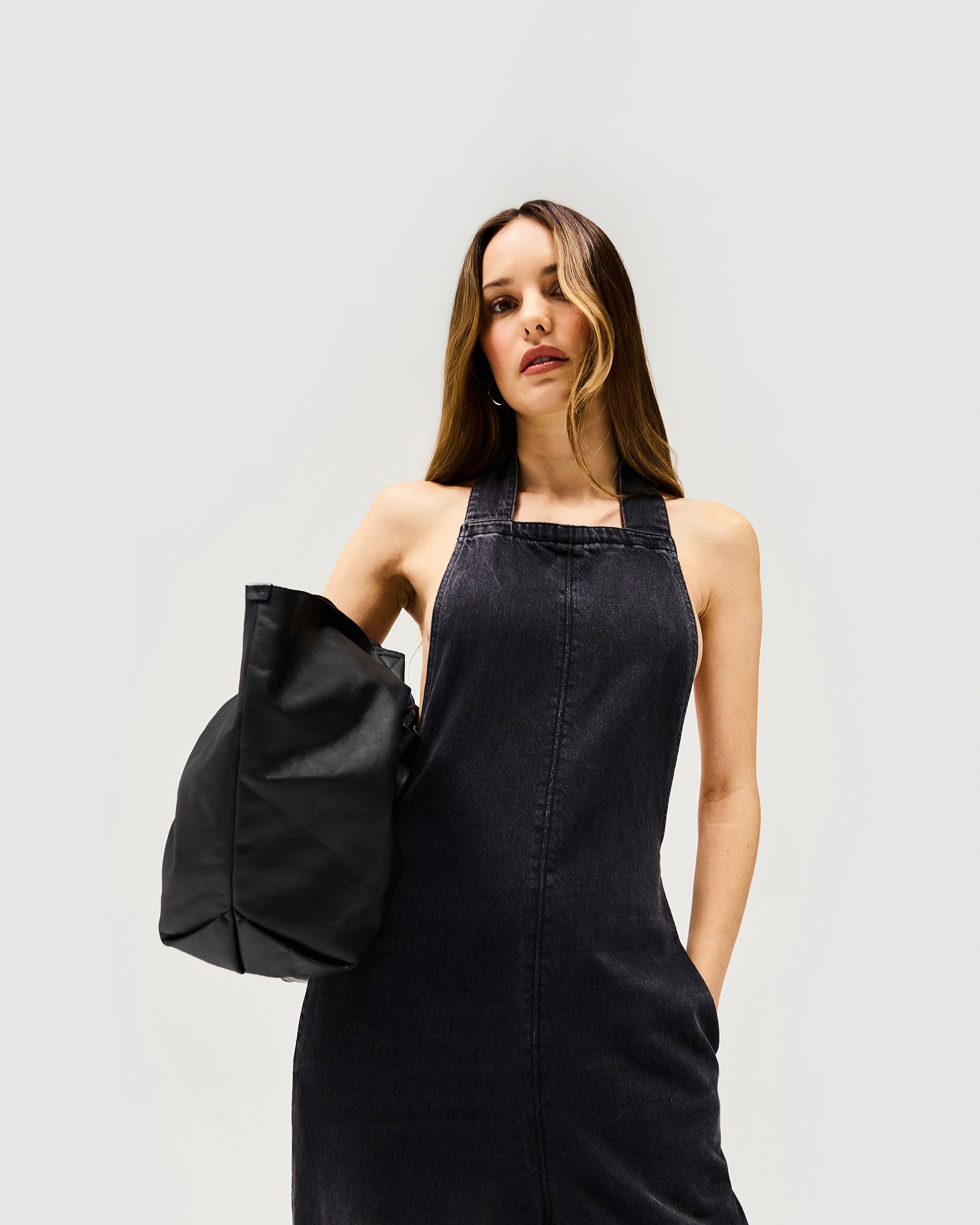 Woman wearing a washed black denim jumpsuit on a plain white background | Voltage Denim Jumpsuit in Washed Black | Wide leg jumpsuit with XL long back tie and drop crotch | Womens SS25 Denim | Represent Clo