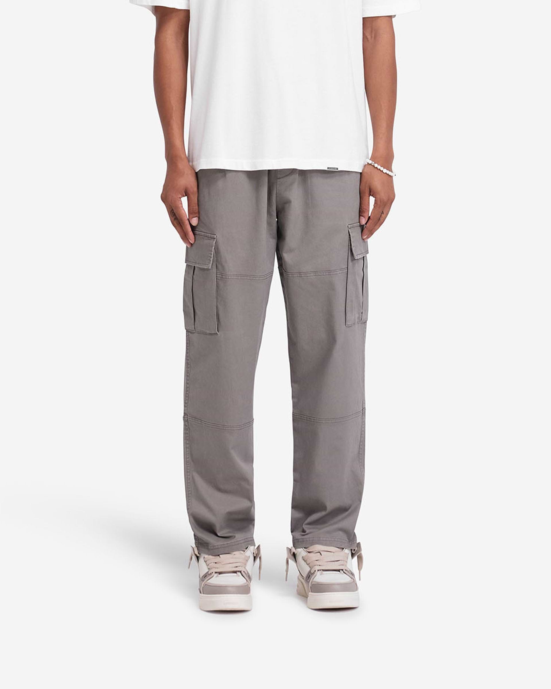 Man wearing dark taupe cargo pants on a plain white background | Cargo Pant in Dark Taupe | Cargo pants with flap pockets and elasticated waistband | FW24 Pants | Represent Clo