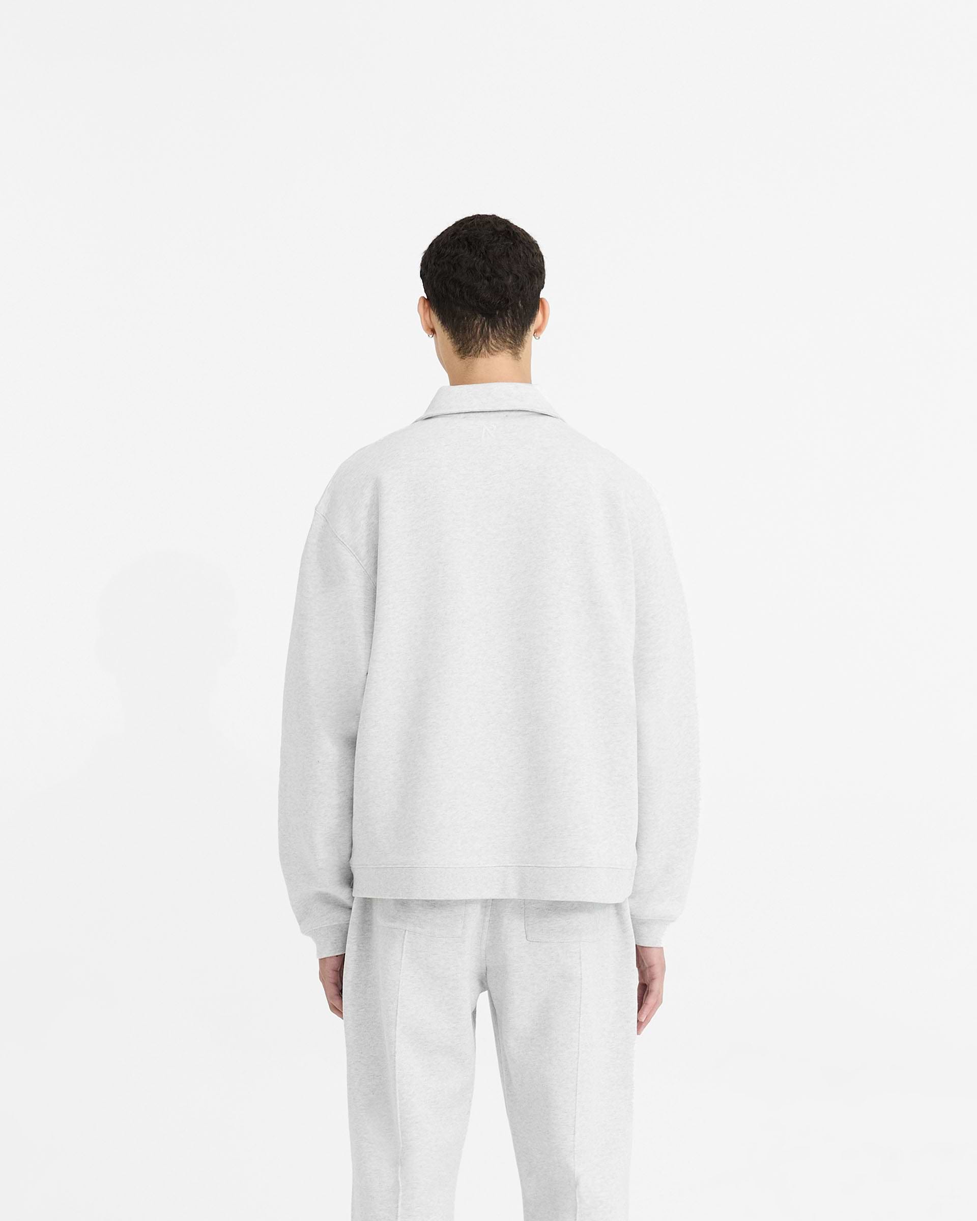 Man wearing an ice grey quarter zip on a plain white background | Initial Boxy Quarter Zip in Ice Grey Marl | Boxy fit cropped sweater with RiRi zip | Initial Sweaters | Represent Clo