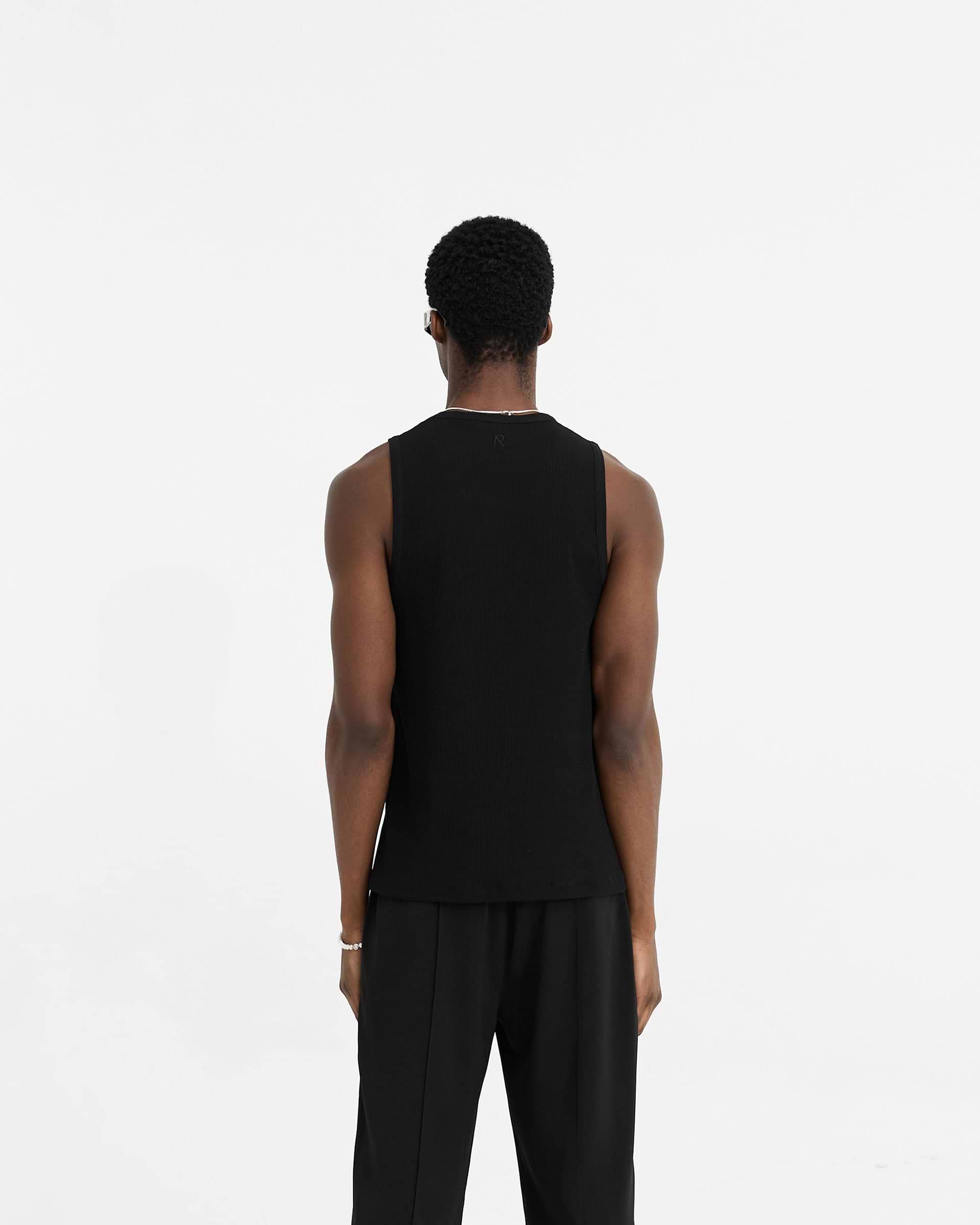 Man wearing a black rib vest on a plain white background | Initial Rib Vest in Black | Lightweight regular fit vest with neck and armhole binding | Initial T-Shirts | Represent Clo