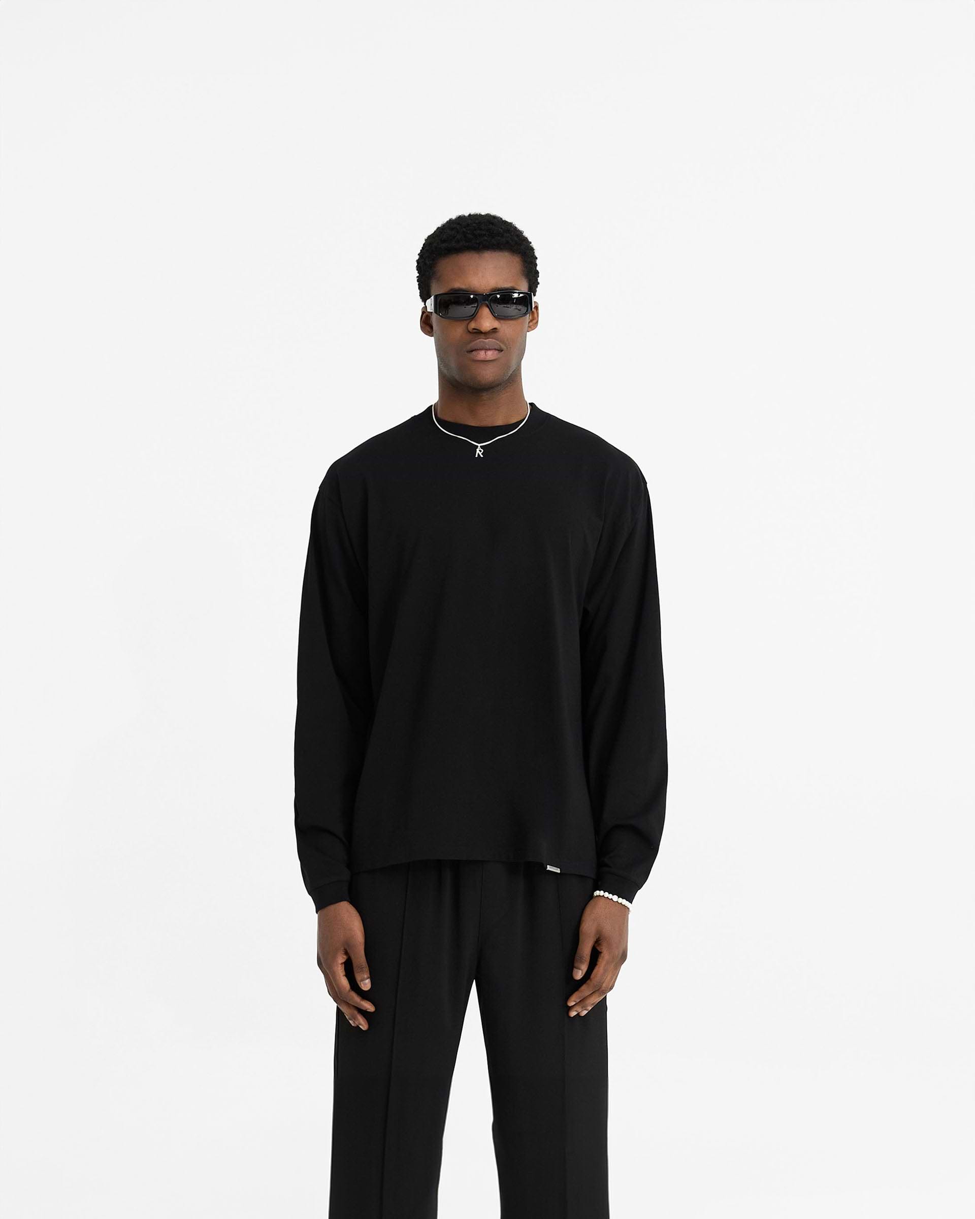 Man wearing a black long sleeve t-shirt on a plain white background | Initial Long Sleeve T-Shirt in Black | Regular fit long sleeve t-shirt with ribbed collar and cuffs | Initial T-Shirts | Represent Clo