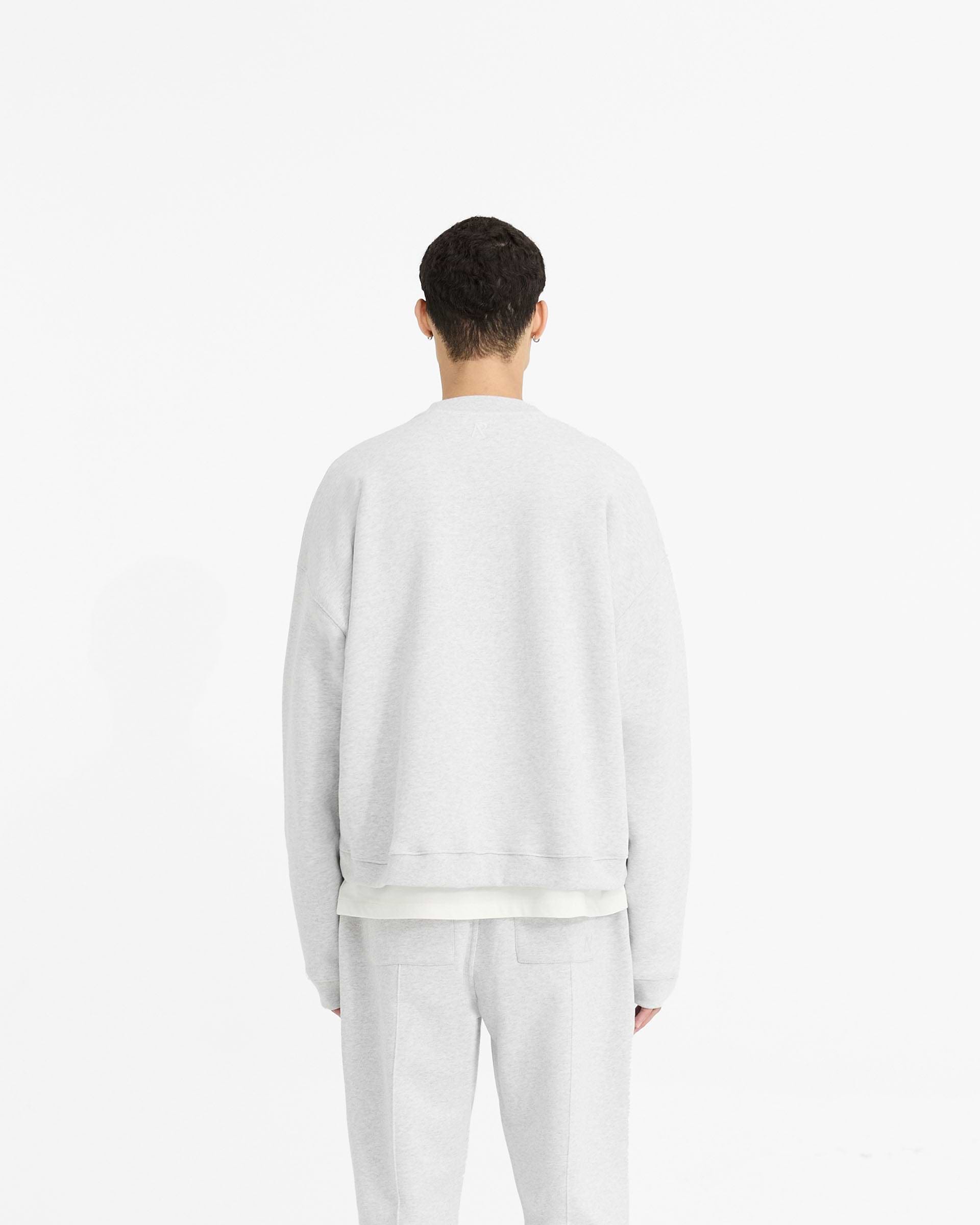 Man wearing a grey sweater on a plain white background | Initial Boxy Sweater in Ice Grey Marl | Boxy heavyweight fleeceback cotton sweater with cropped fit | Initial Sweaters | Represent Clo