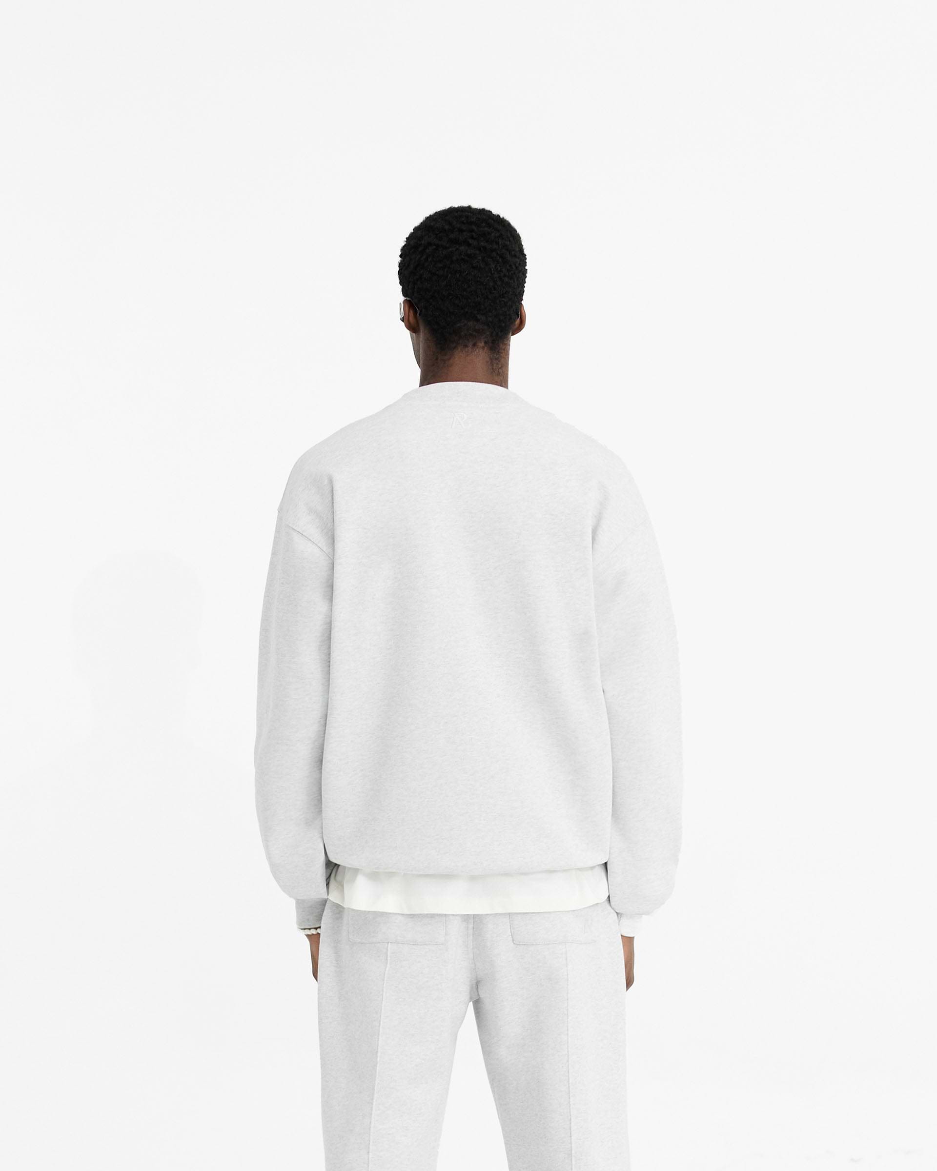 Man wearing a grey sweater on a plain white background | Initial Oversized Sweater in Ice Grey Marl | Slightly oversized sweater in organic cotton | Initial Sweaters | Represent Clo