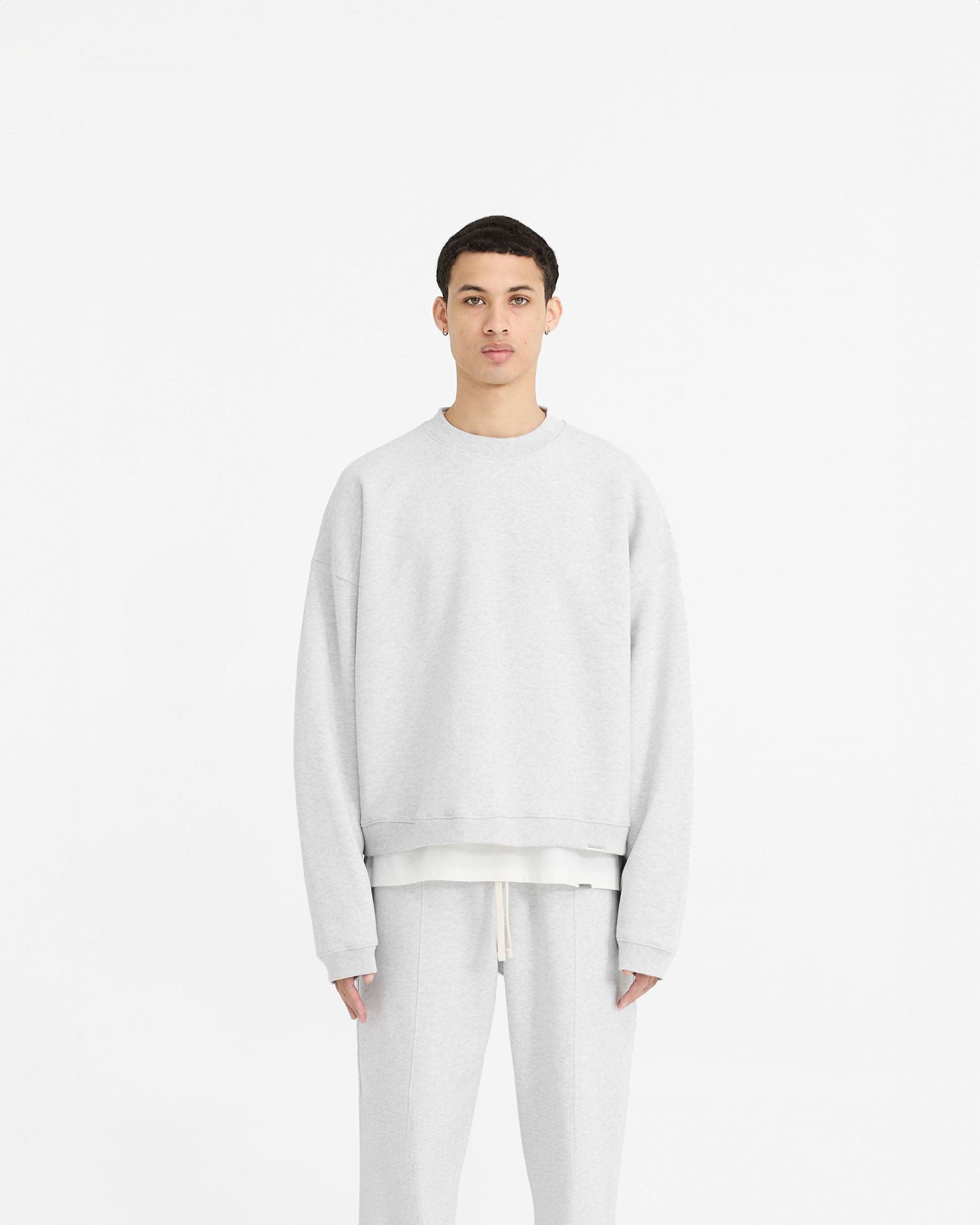Man wearing a grey oversized sweater on a plain white background | Initial Boxy Sweater in Ice Grey Marl | Boxy fit sweater with dropped shoulders | Initial Sweaters | Represent Clo