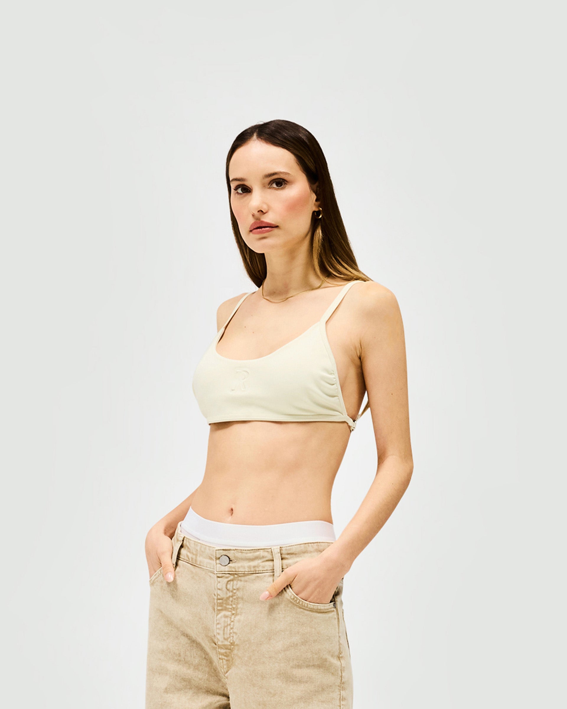 Woman wearing a warm white bralette on a plain white background | Control Bralette in Warm White | Neoprene bralette with adjustable fit | Womens SS25 Tops | Represent Clo
