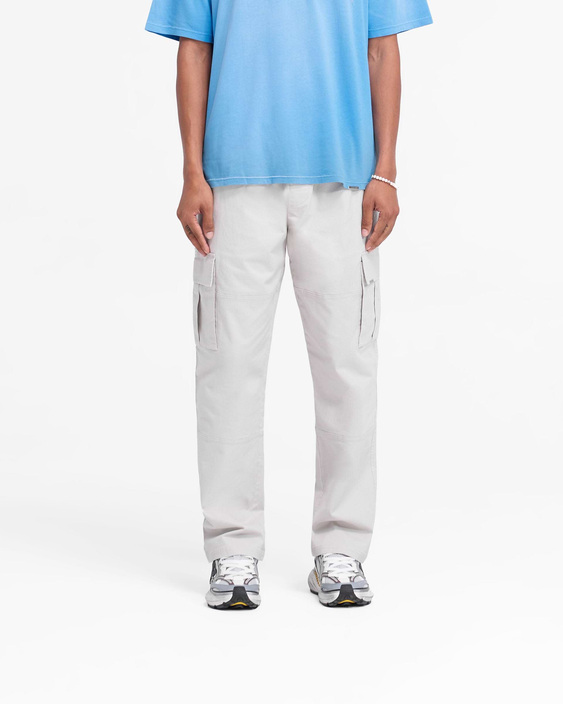 Man wearing stone pants on a plain white background | Cargo Pant in Stone | Regular fit cargo pants with elasticated waistband and flap pockets | FW24 Pants | Represent Clo