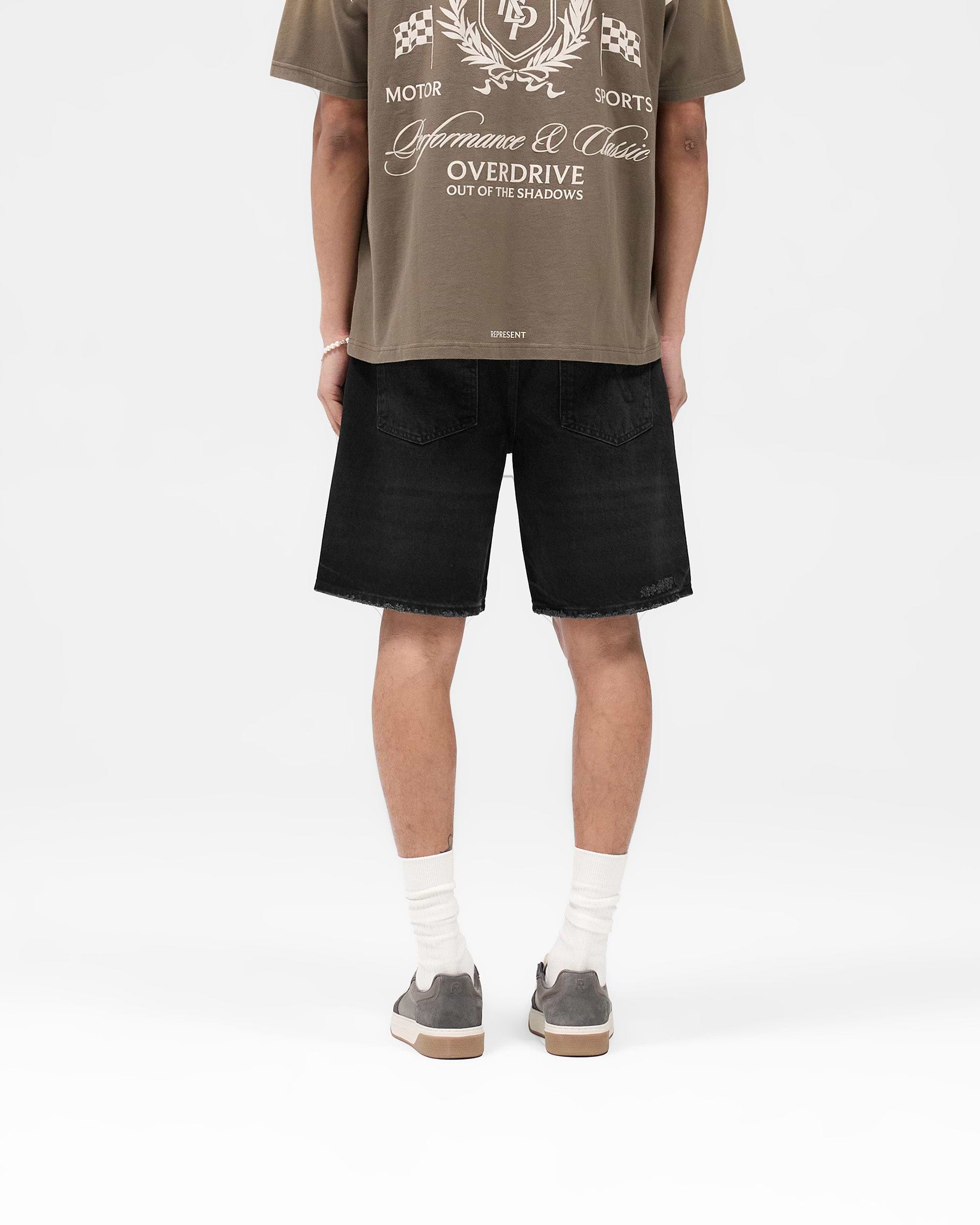 Man wearing black denim shorts on a plain white background | R10T Tailored Denim Shorts in Black | Tailored denim shorts with vintage-inspired faded wash | SS25 Denim | Represent Clo