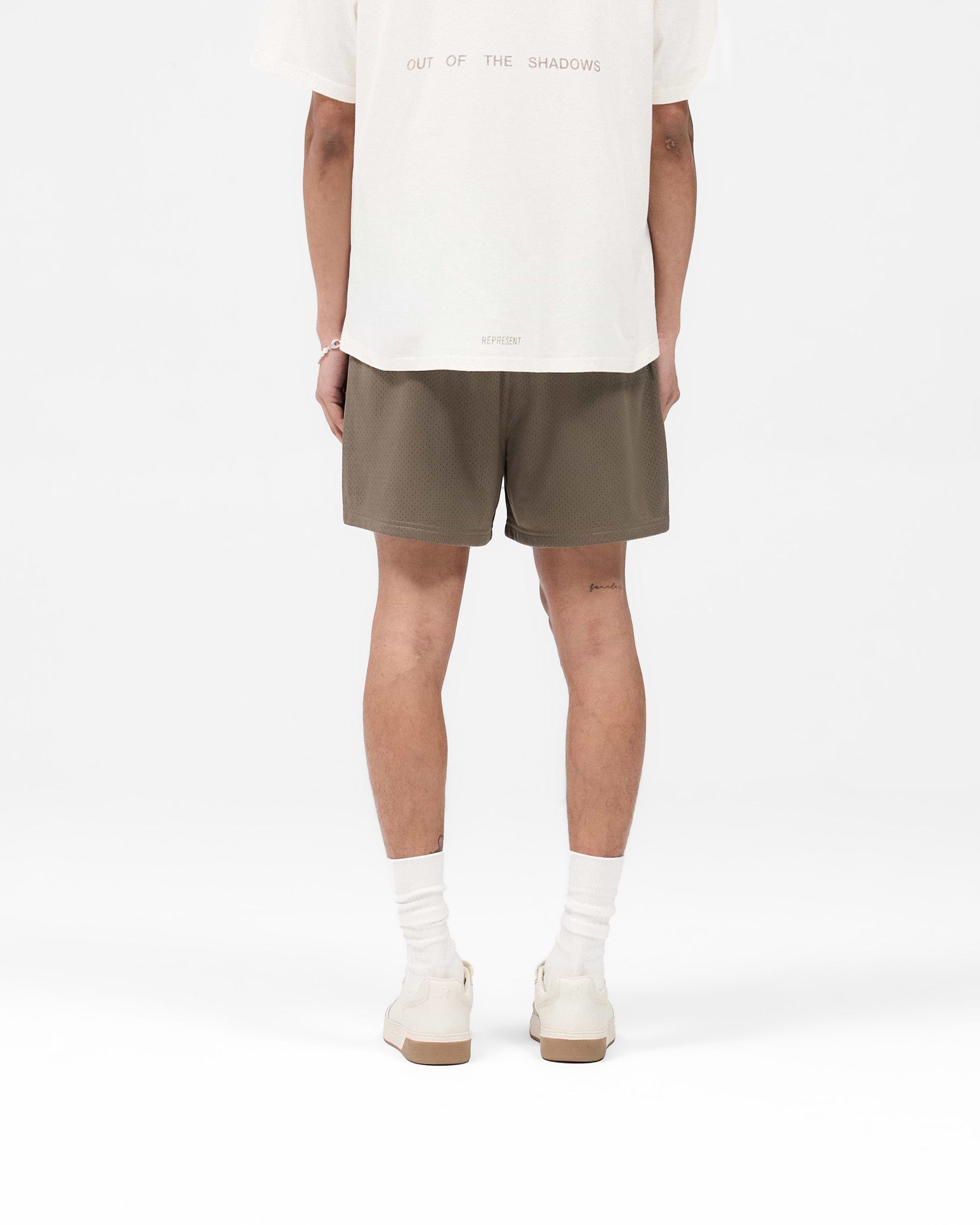 Man wearing stone mesh shorts on a plain white background | Mesh Short in Stone | Mesh shorts with zip pockets and internal drawcord | SS25 Shorts | Represent Clo