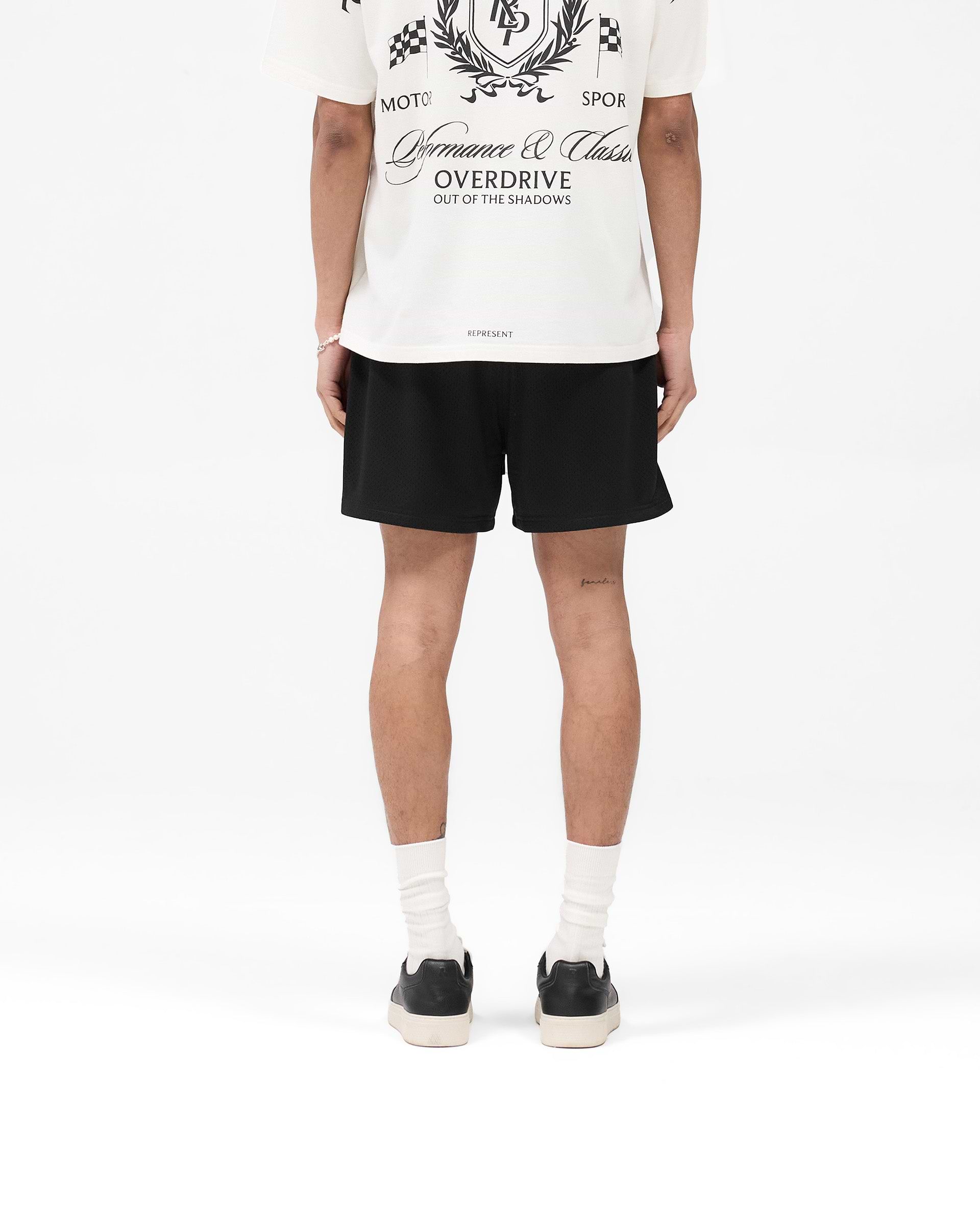 Man wearing black mesh shorts on a plain white background | Mesh Short in Black | Mesh shorts with internal drawcord and side pockets | SS25 Shorts | Represent Clo