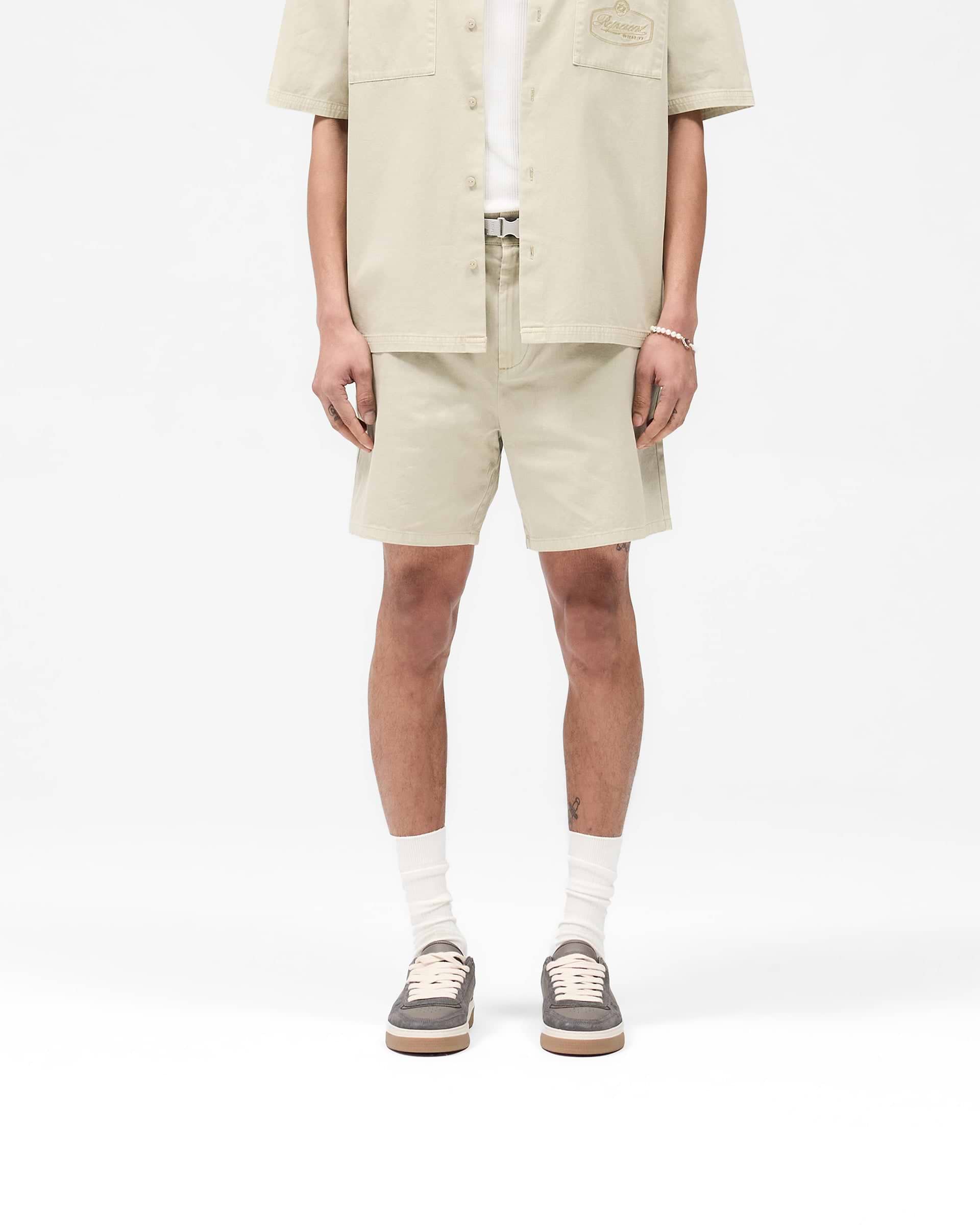 Man wearing beige shorts on a plain white background | Cotton Tailored Short in Beige | Tailored shorts with structured silhouette | SS25 Shorts | Represent Clo