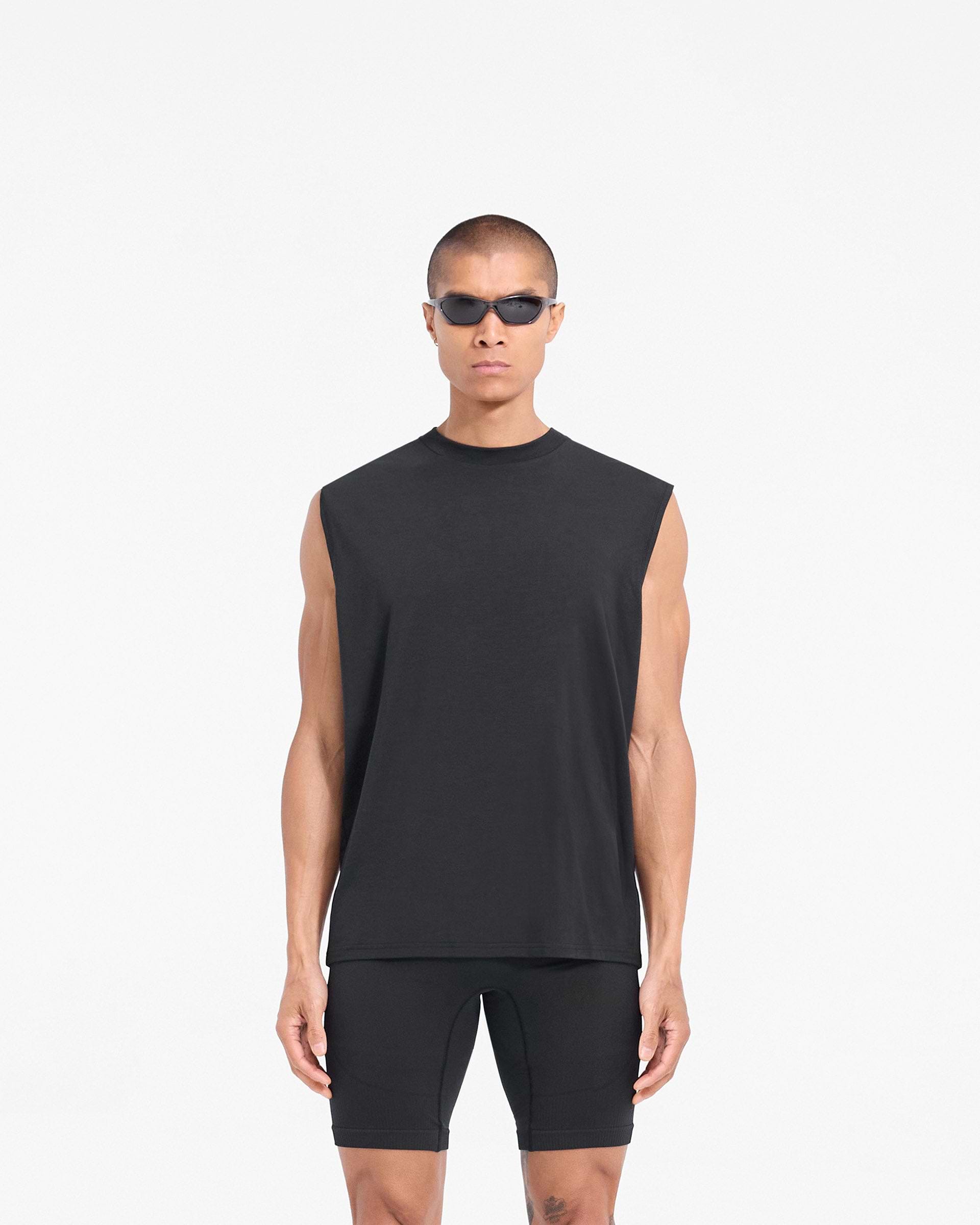 Man wearing a black tank top on a plain white background | 247 DNA Oversized Tank in Black | Lightweight gym tank with oversized fit | 247 T-Shirts | Represent Clo