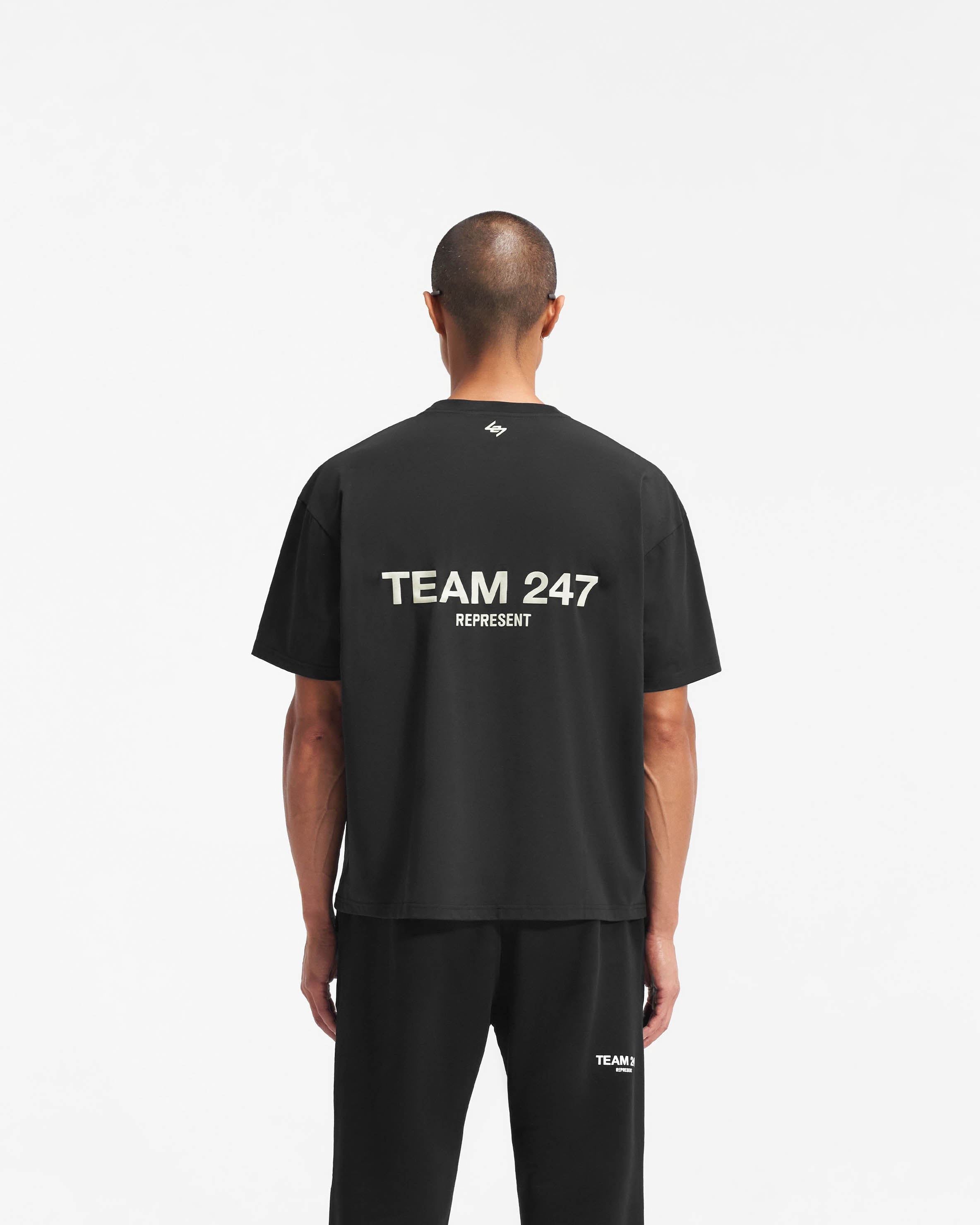 Man wearing a black oversized t-shirt on a plain white background | Team 247 Oversized T-Shirt in Black | Lightweight quick dry oversized gym top | 247 T-Shirts | Represent Clo