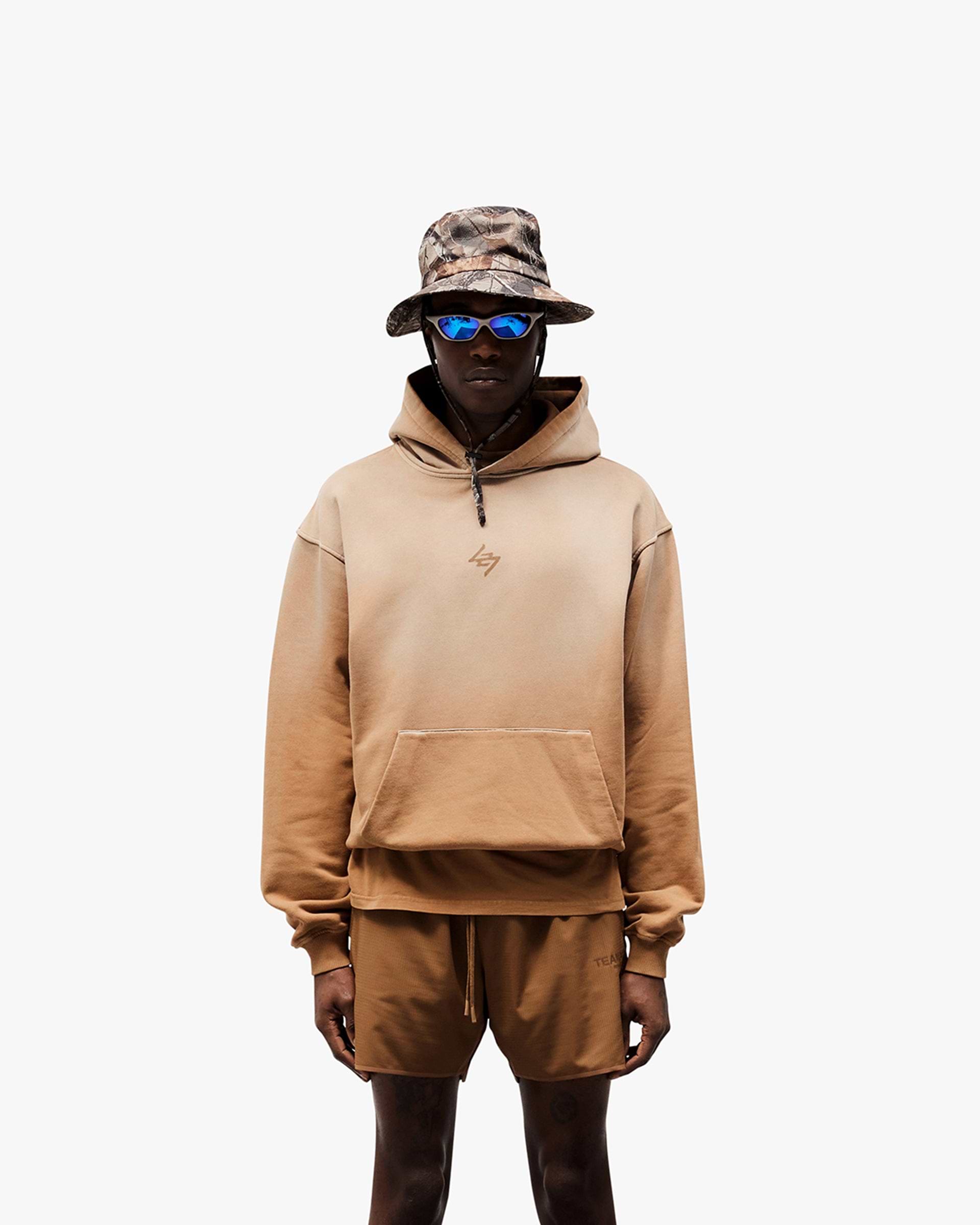 Man wearing an oversized rust hoodie on a plain white background | 247 Motion Oversized Hoodie in Rust | Hoodie with vintage wash and tonal drawcords | 247 Hoodies | Represent Clo