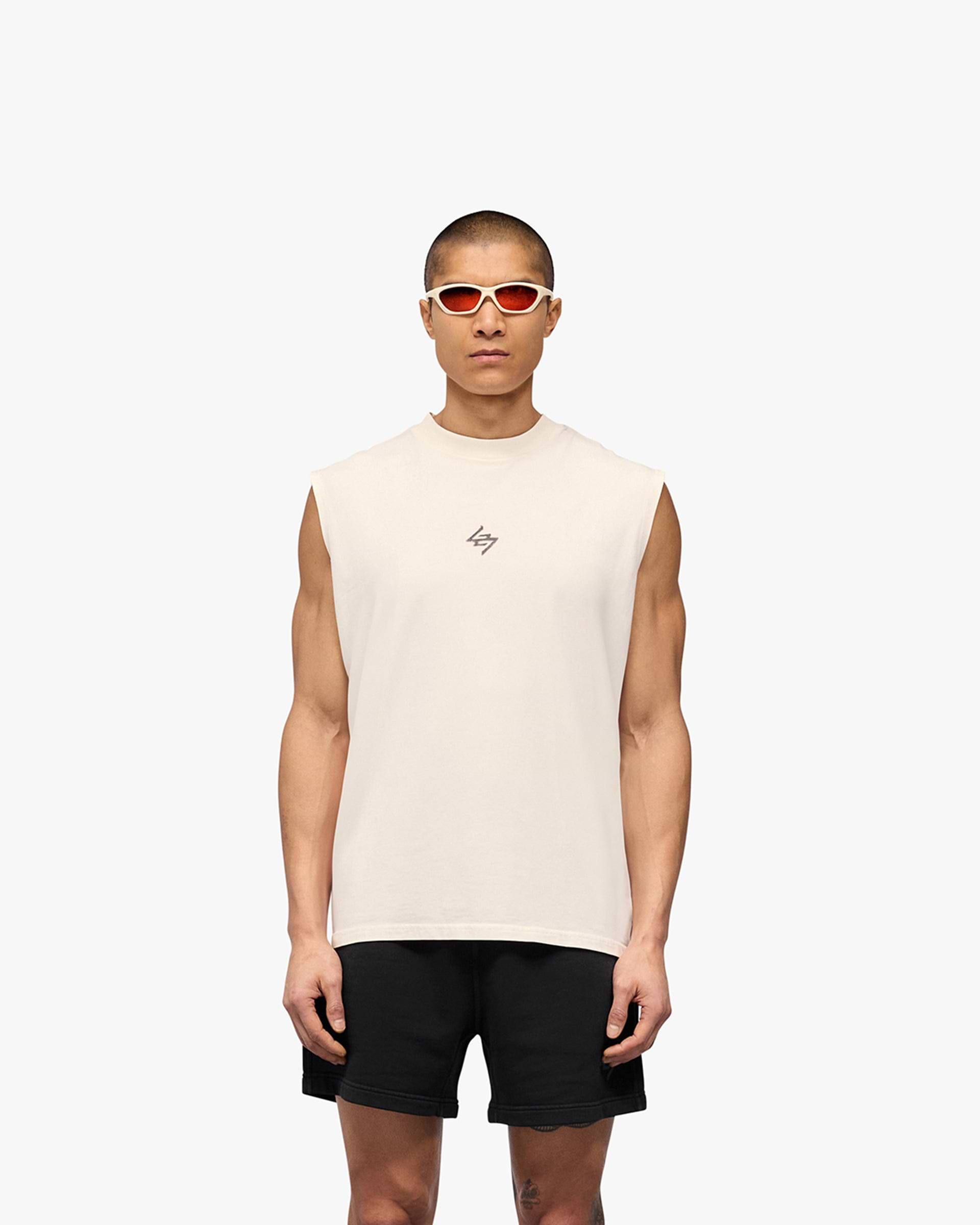 Man wearing a white tank top on a plain white background | 247 Motion Oversized Tank in Flat White | Oversized tank top with graphic print | 247 T-Shirts | Represent Clo