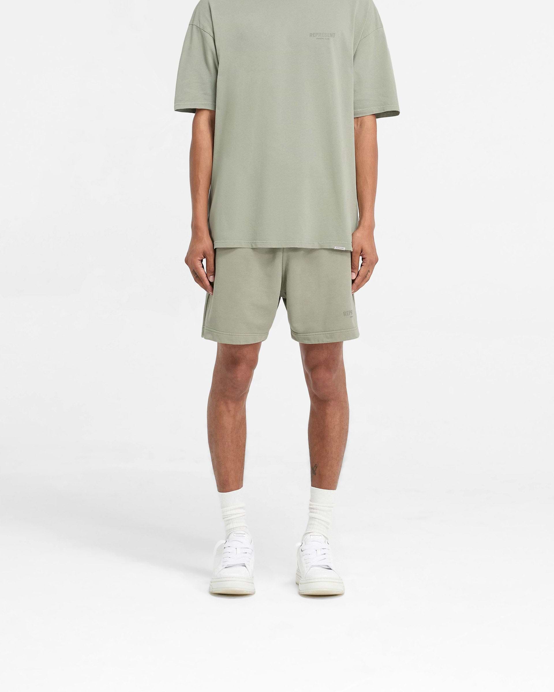 Man wearing pastel green shorts on a plain white background | Represent Owners Club Shorts in Pastel Green | Heavy weight jersey cotton shorts with elasticated waistband | Owners Club Shorts | Represent Clo
