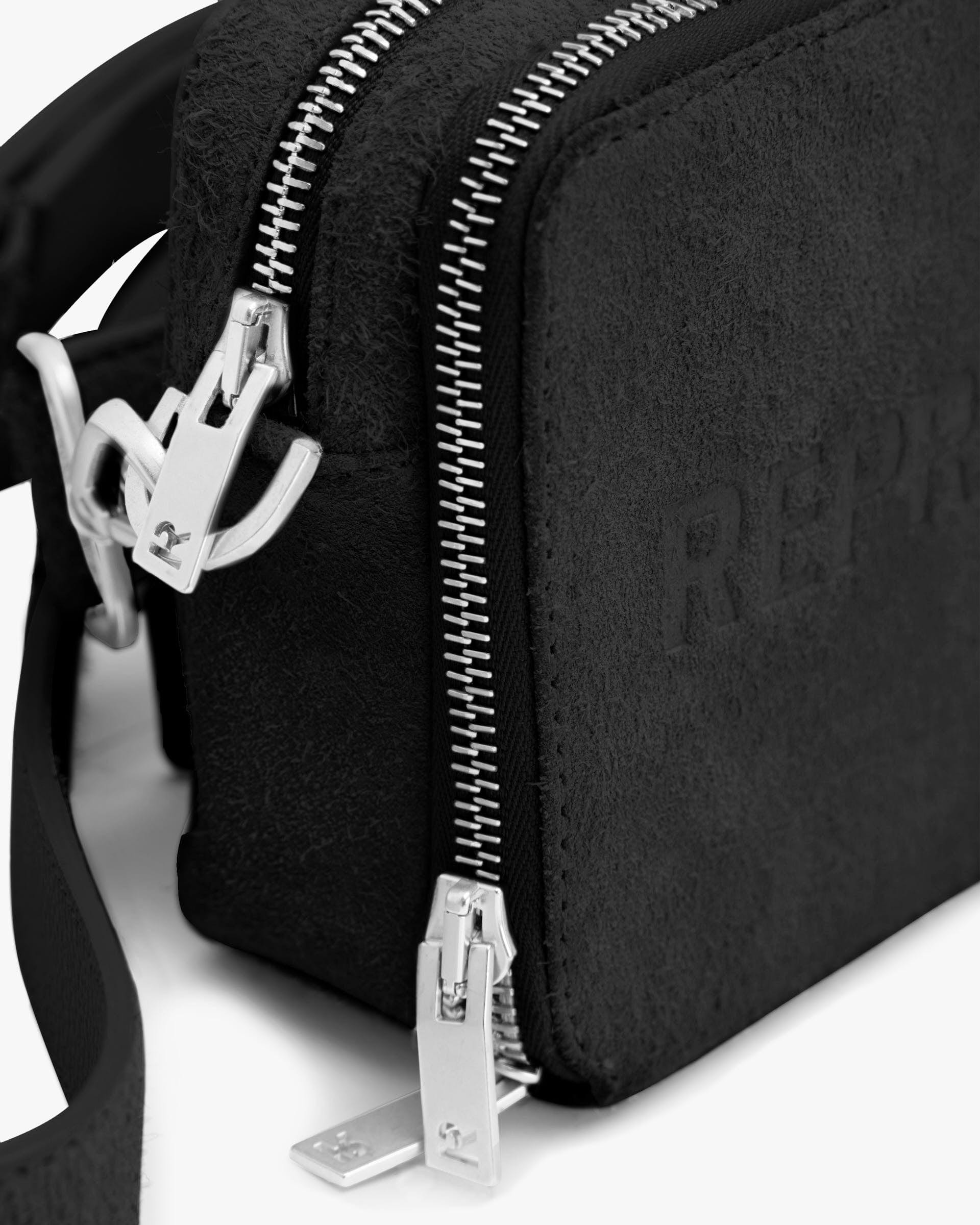 Back product image of a black suede camera bag on a plain white background | Represent Hairy Suede Camera Bag in Black | Suede camera bag with adjustable strap and wallet slip pockets | SS24 Accessories | Represent Clo