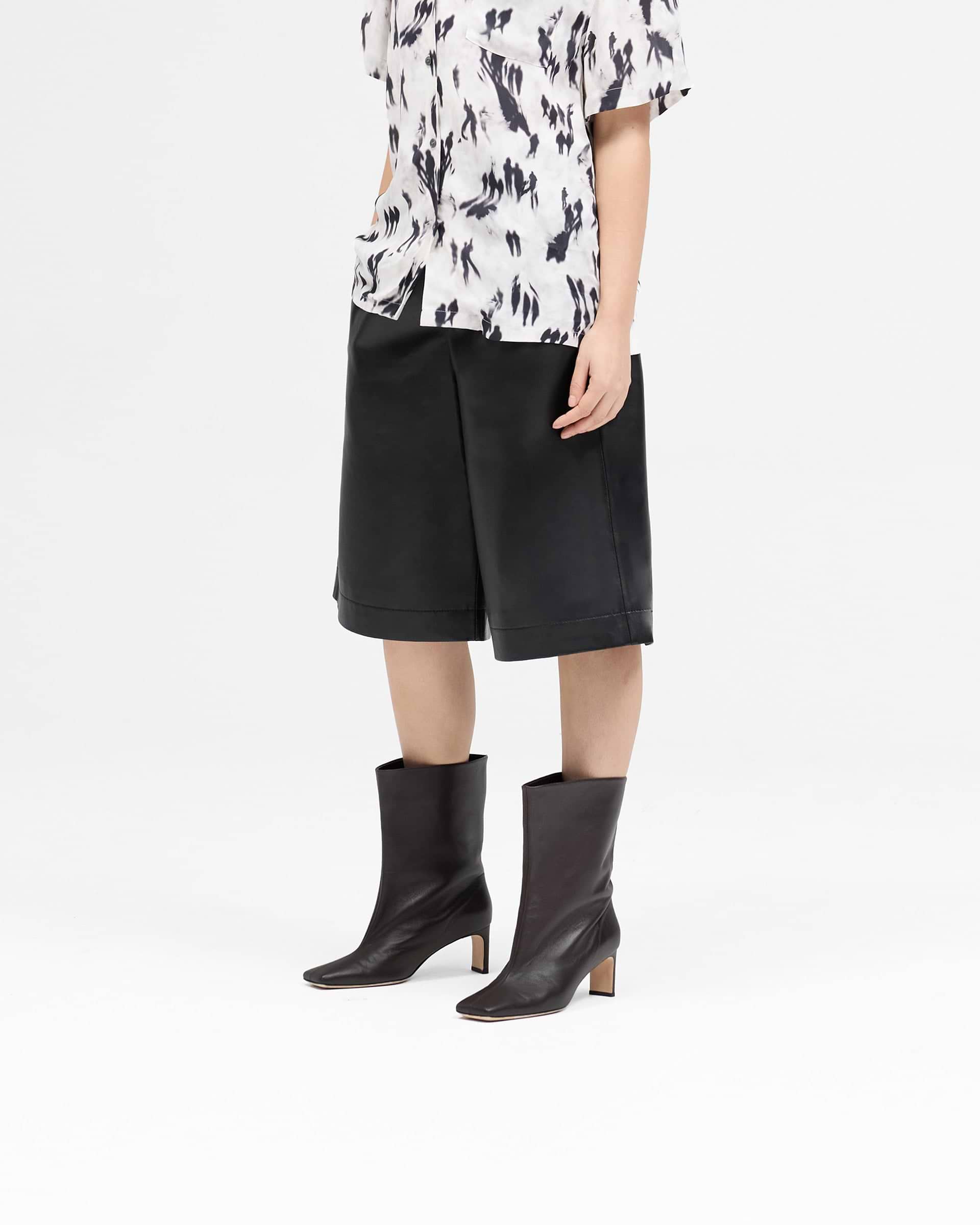 Back product image of a womens black leather shorts on a plain white background | Fuel Shorts in Jet Black | Leather Bermuda style shorts with elasticated waist and wide leg | Womens SS25 Shorts | Represent Clo