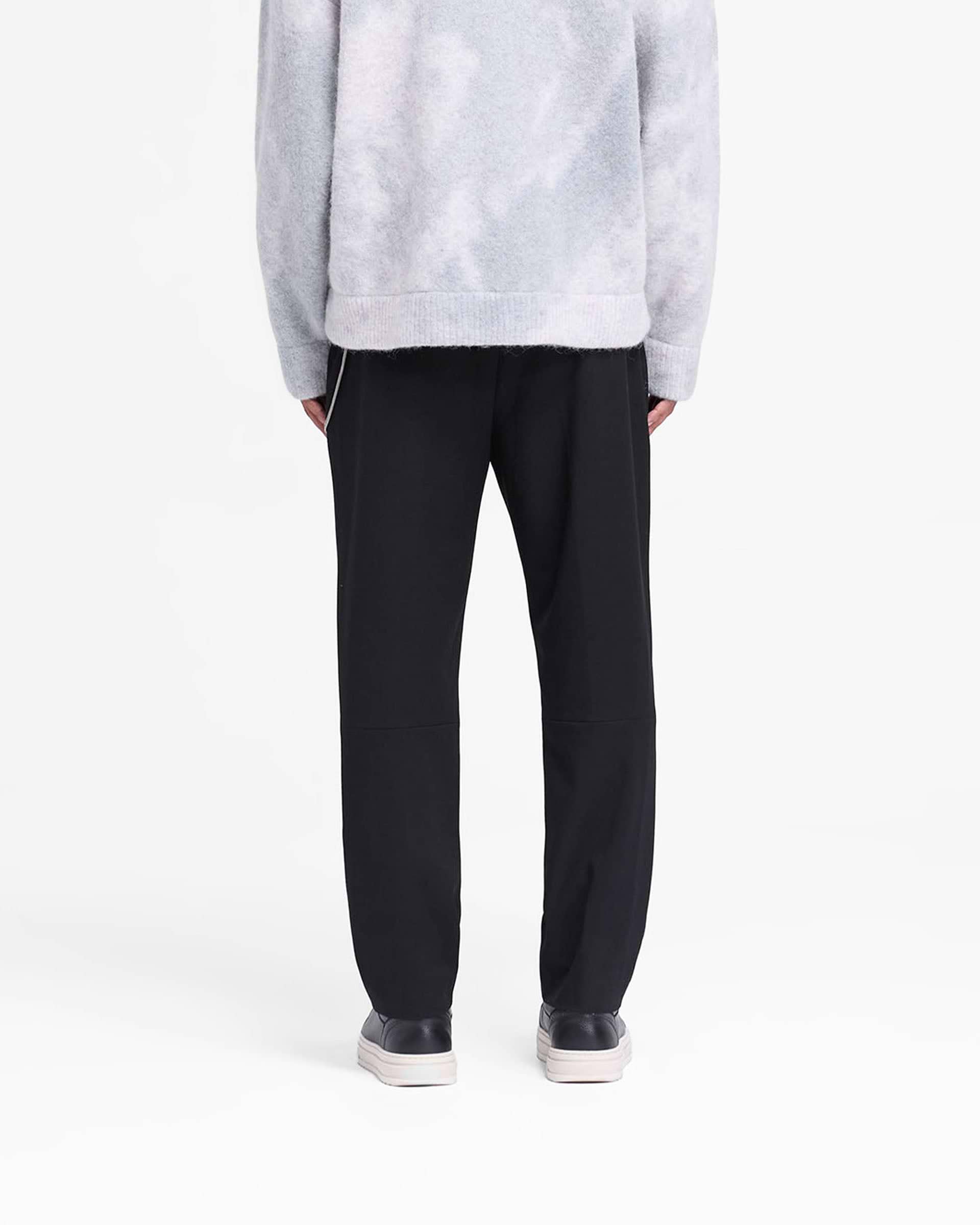 Man wearing black pants on a plain white background | Smoking Pant in Black | Smart slim silhouette pants with cropped length and fixed waistband | FW24 Pants | Represent Clo