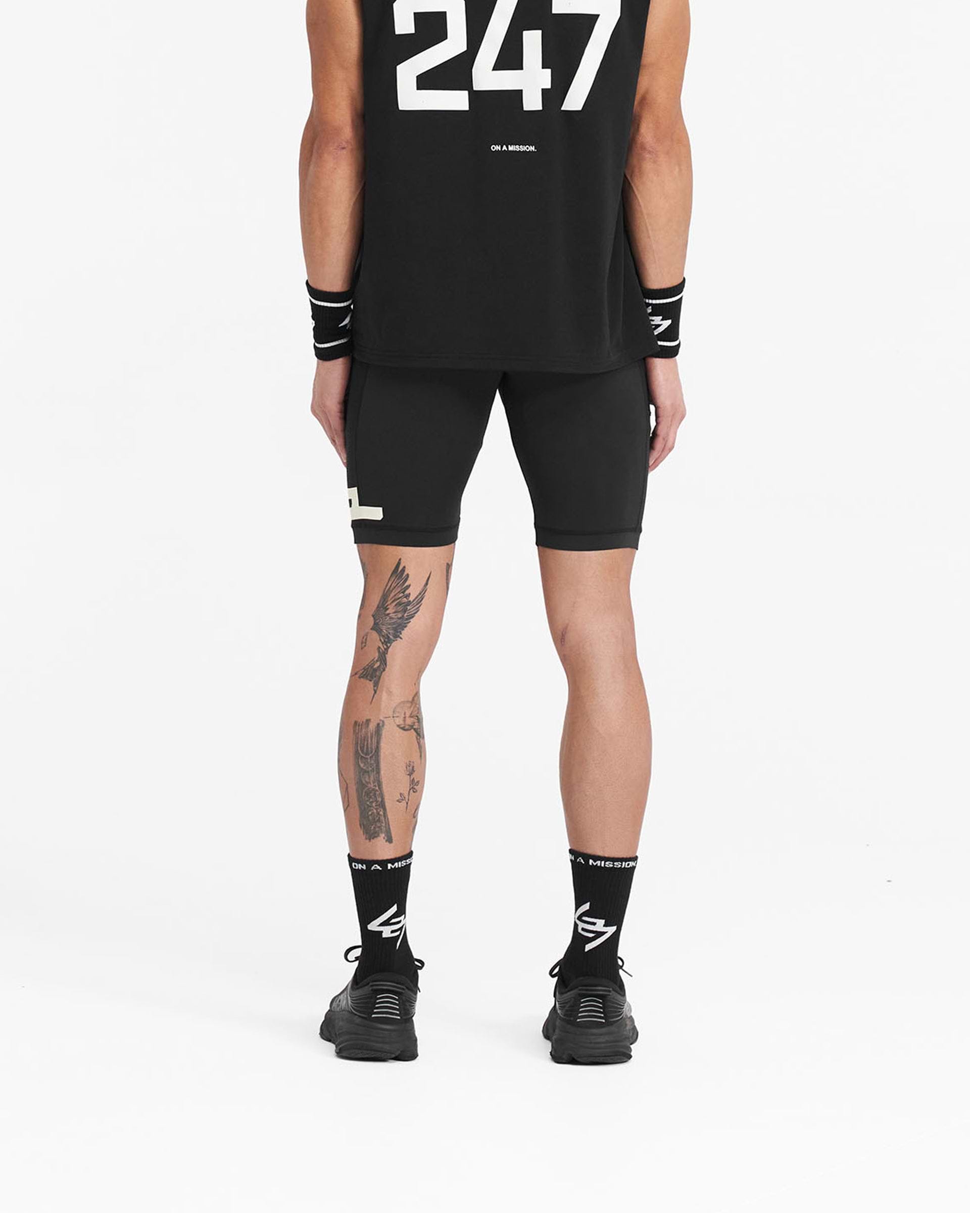 Man wearing black cargo half tights on a plain white background | 247 Cargo Half Tight in Jet Black | Cargo half tights with stretch ripstop side panelling | 247 Shorts | Represent Clo
